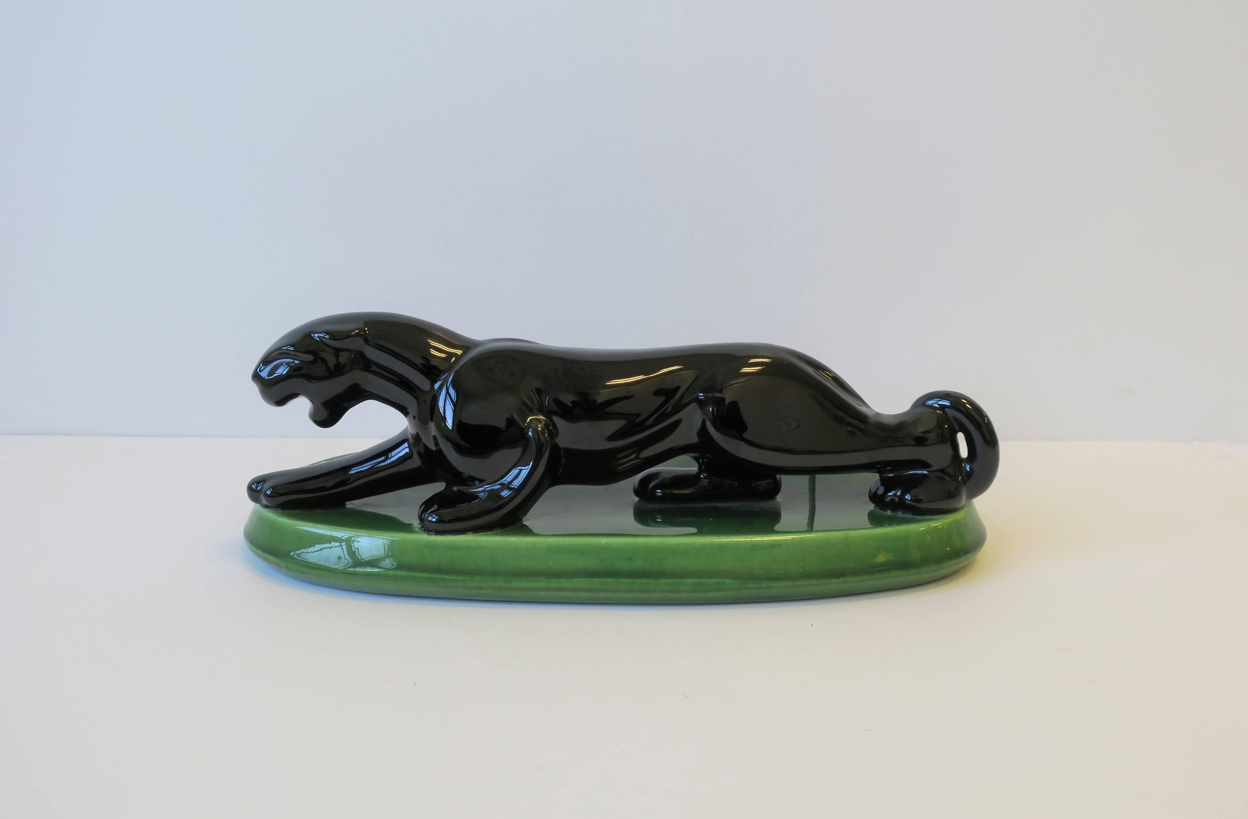 Magnifique et élégant chat panthère en céramique noire Art Déco sur base ovale par Haeger:: vers le début du 20e siècle. Pièce marquée sur le bas comme indiqué sur l'image n°9. Les couleurs comprennent : Noir et vert. 

La pièce mesure : 6.5