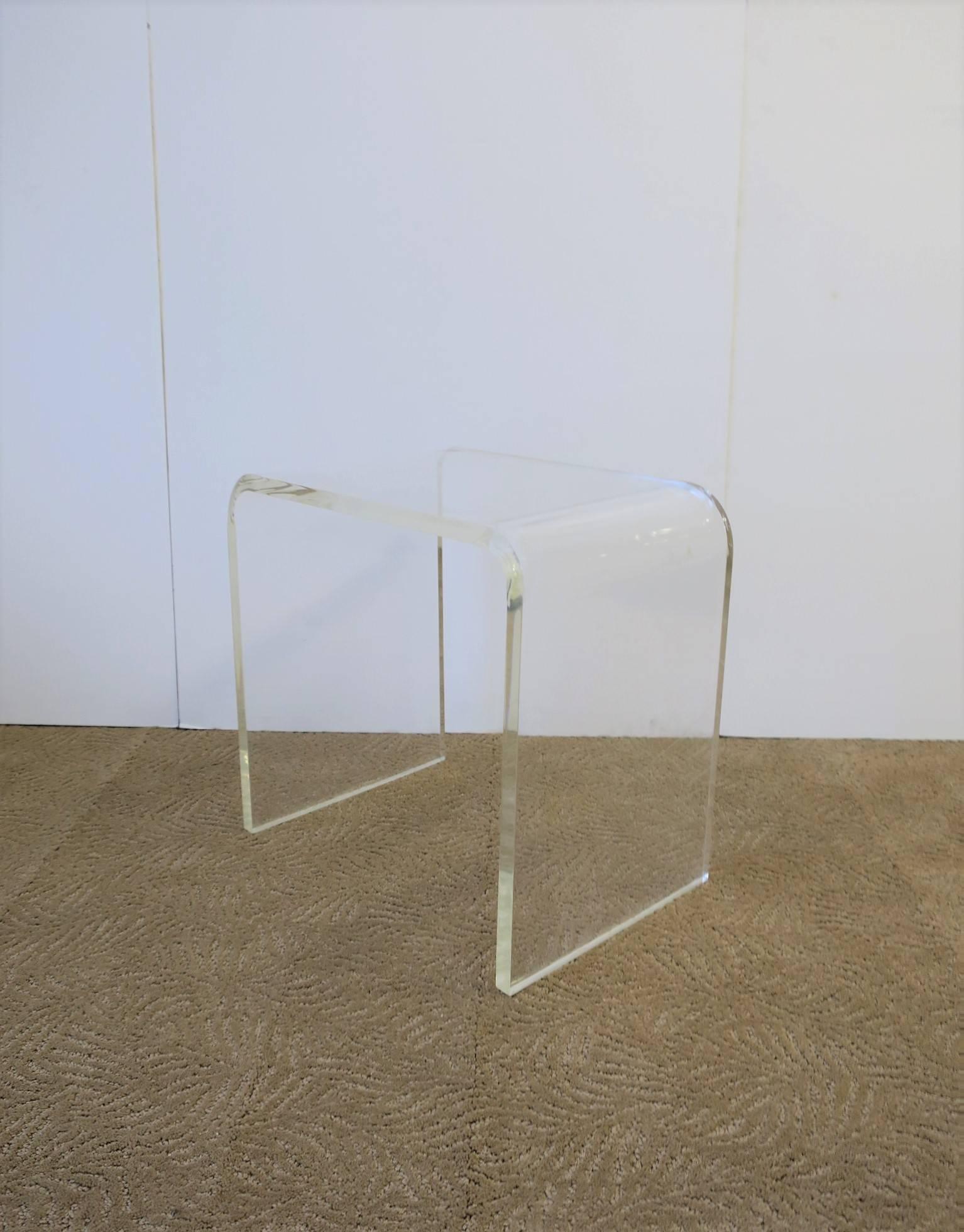 A Modern style Lucite 'waterfall' bench, end or side table. Piece is made from one piece of Lucite at approximately 1 inch thick. Piece is in the style of American designer Charles Hollis Jones. 

Piece measures: 17.75 in. W x 12 in. D x 17 in.