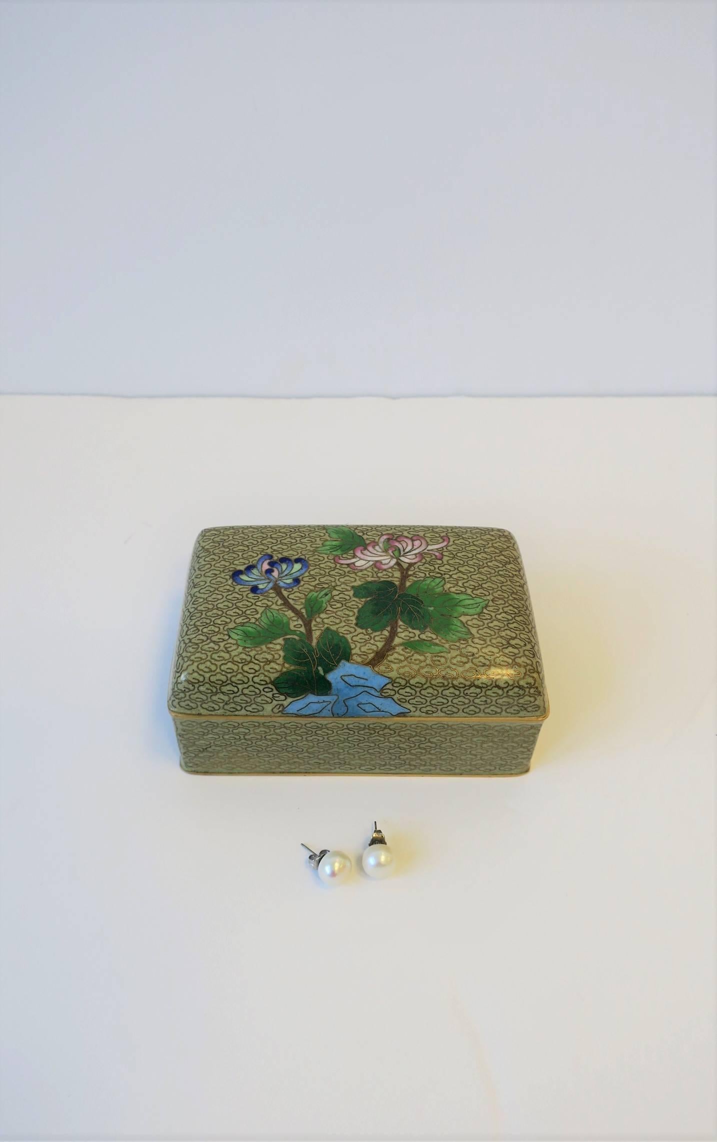 A beautiful vintage Chinese Cloisonné enamel and brass decorative desk, jewelry or trinket box. Two decorative mum flowers on front. Colors include: gold/brass, blue, white, pink, emerald green, brown and cream/sand hues. Excellent vintage