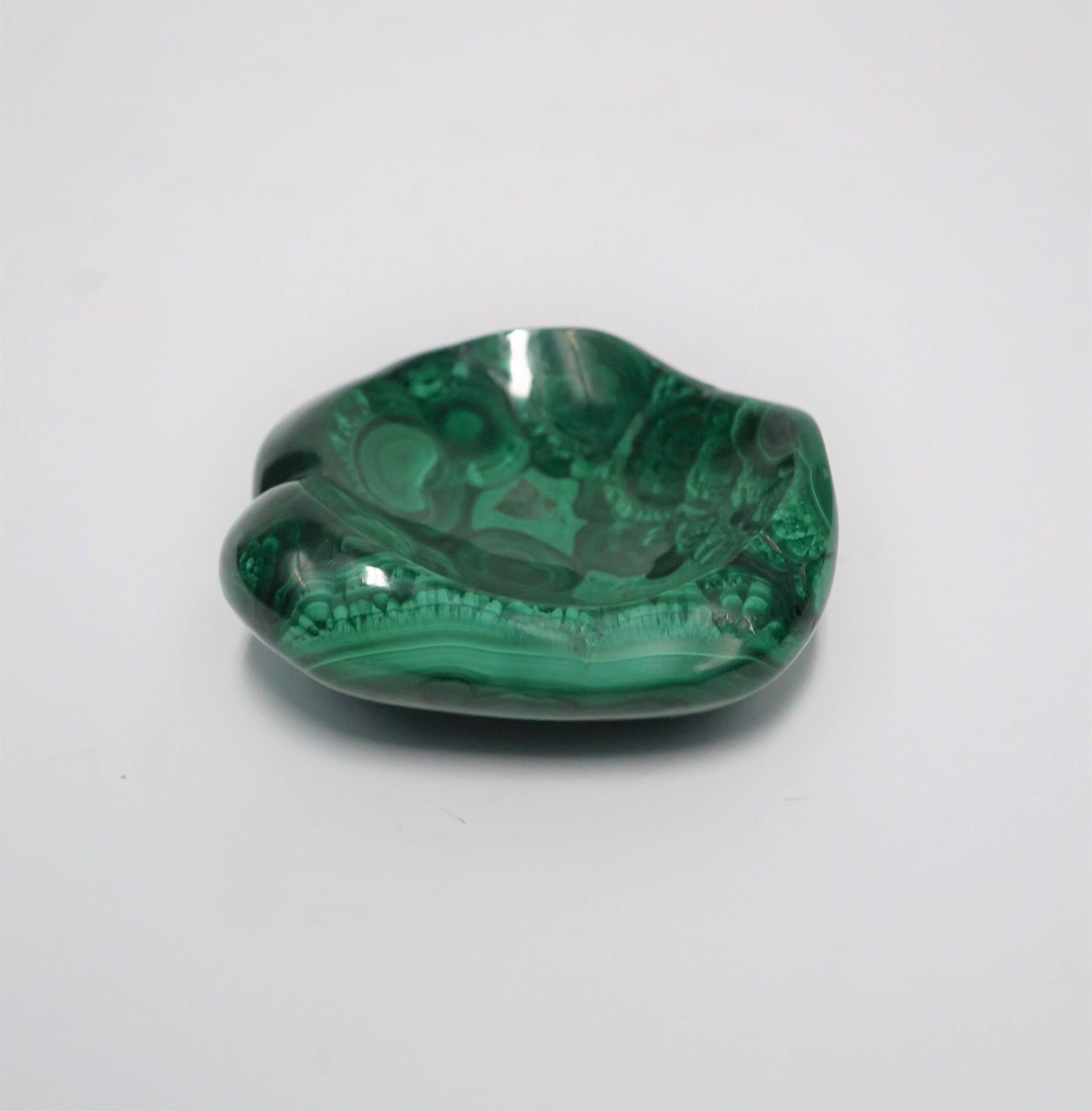 A small emerald green malachite bowl, trinket or jewelry dish; piece can be used on a desk, vanity, or other area to hold small items. A beautiful malachite vessel, polished smooth. 

Piece measures approximately: 3.25 in. D x 1.25 in. H 

Item