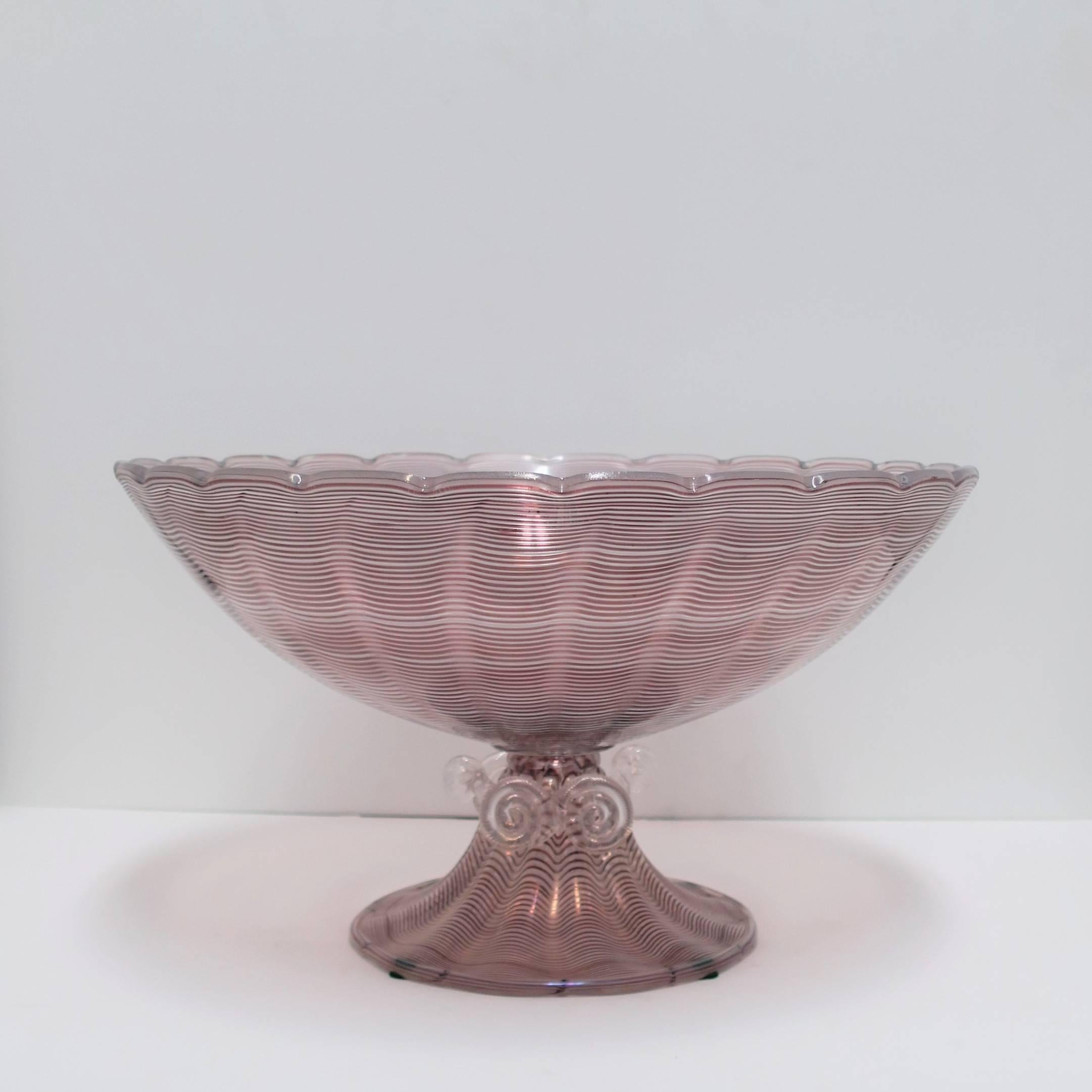 A very beautiful and relatively large vintage Italian Murano art glass urn form centerpiece bowl. Piece has a scalloped edge around top and clear applied art glass swirls on base. Centerpiece hues are purple/amethyst or plum and white-clear