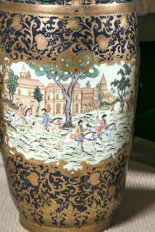 Pair of 20th century Chinese export palace vases with English colonial hunt scenes, overall scrolled gold floral design over cobalt ground with applied goose handles and salamander motif on the necks.