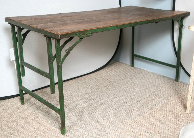 Vintage French folding table with iron legs that can be used for dining height or coffee style size. Lovely patina wooden top with green painted iron retractable legs
