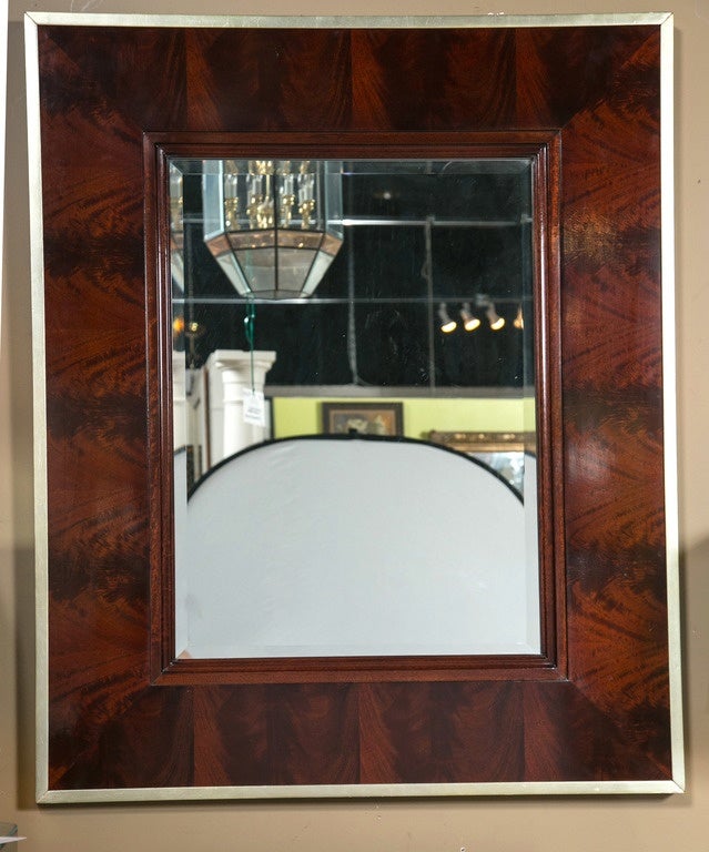 This modern flame mahogany Burke mirror with beveled glass is from Thomas O'Brien's first collection for Hickory Chair Co. The matched flame mahogany paneled frame is bordered in antiqued silver leaf.
