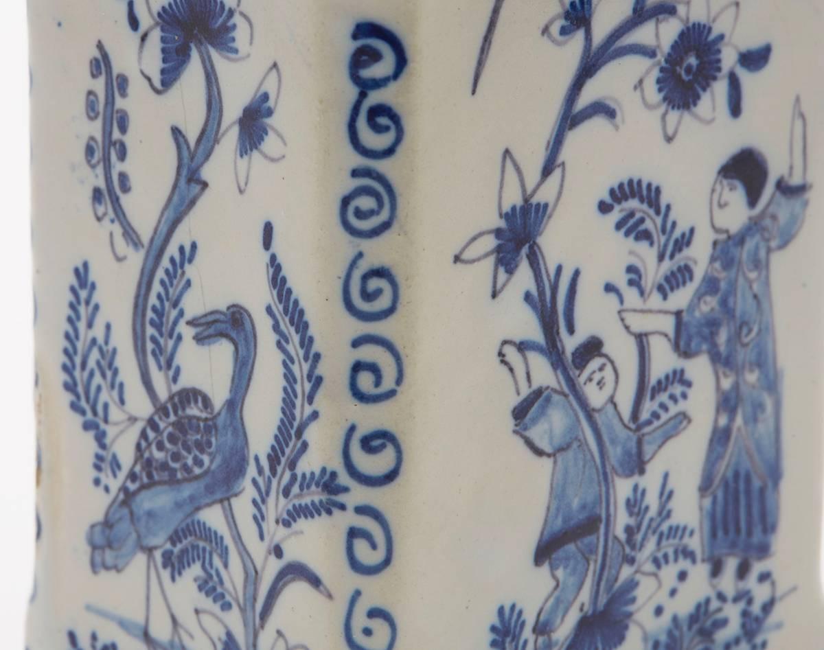 A fine antique delft faience blue and white earthenware lidded tea caddy hand decorated with figural scenes in chinoiserie style with side panels with exotic birds. Raised on four corner feet the rectangular caddy has an angled top rim and small