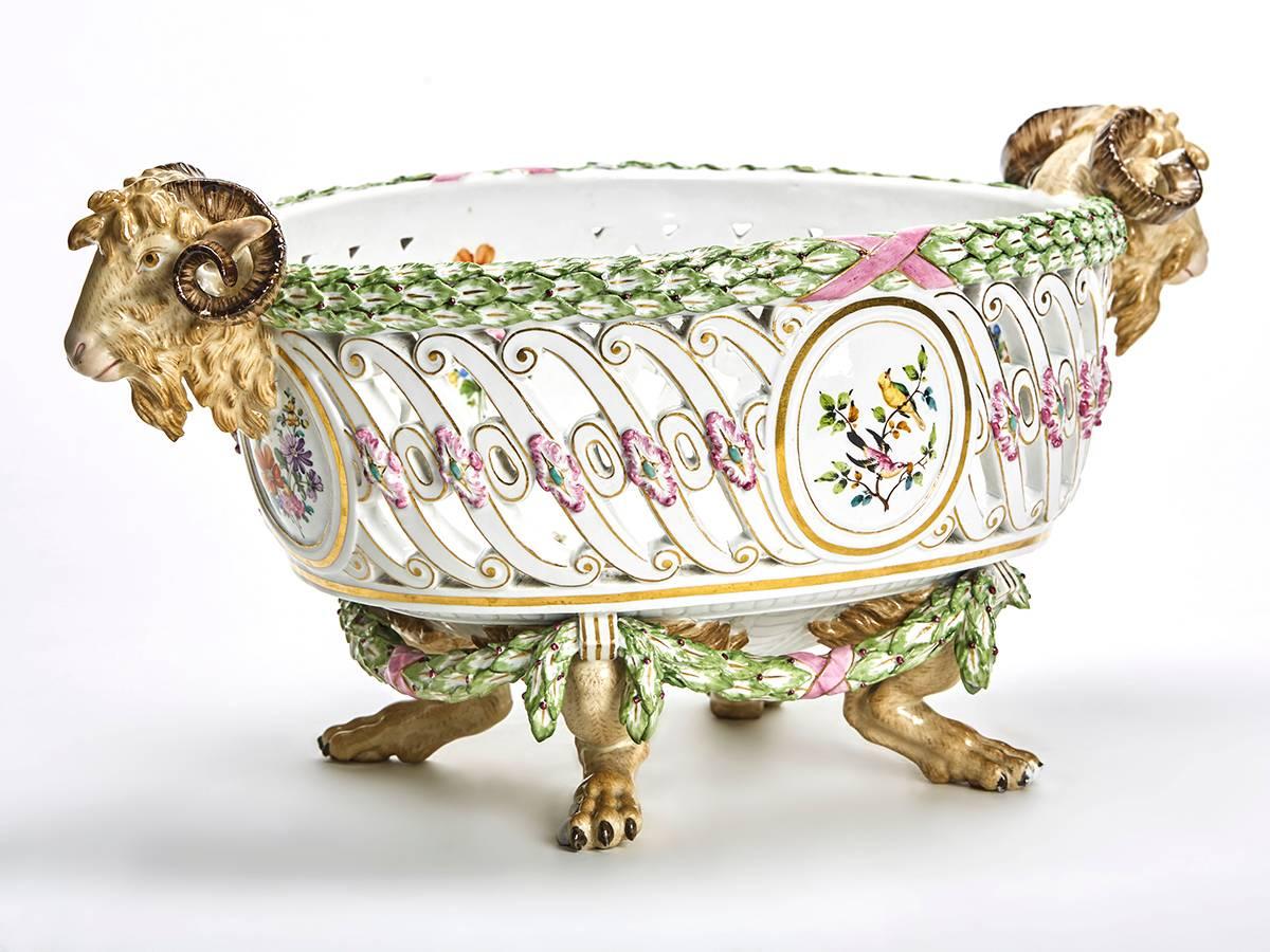 A stunning antique German Meissen pierced porcelain twin handled footed basket, after Schoenheit. The oval body is pierced with a central frieze if S-scrolls and painted with two circular panels of birds on branches and two with floral sprays