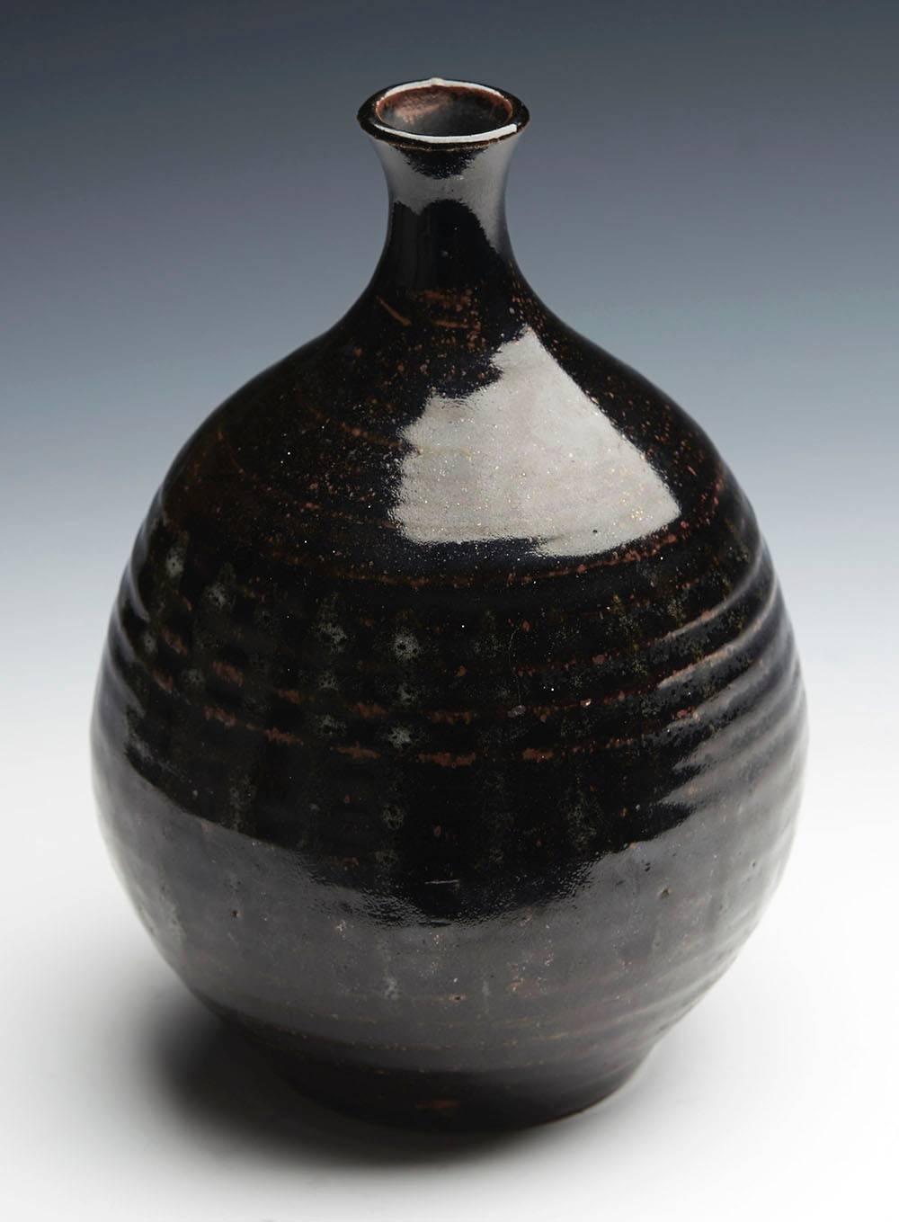 An antique Japanese stoneware bottle shaped vase decorated in tenmoku glazes and possibly dating from the 18th-19th century. This very stylish stoneware vase stands on an unglazed rounded foot with a slightly recessed base and has a rounded bulbous