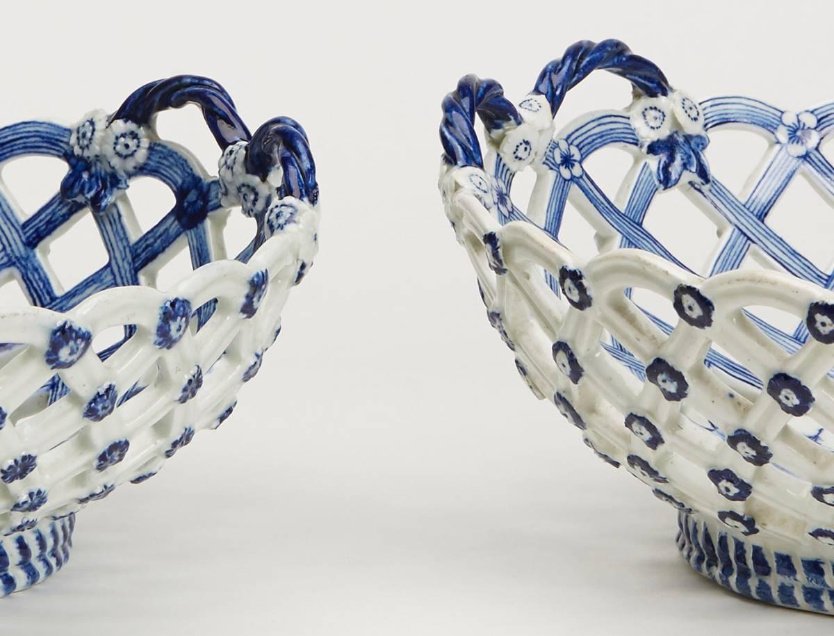 A very rare pair antique Derby Porcelain reticulated twin handled baskets with gently curved trellis sides hand-painted in blue and white with chinoiserie scenes. The exterior is applied in relief with florets with a double rope twist band around