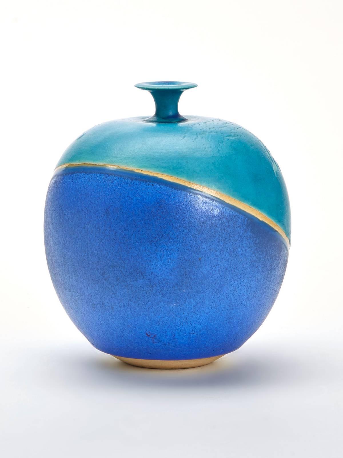 A vintage Studio Pottery modernist vase of rounded shape decorated in blue and turquoise glazes with an unglazed band around the body. The vase has a narrow raised flat formed top and is signed Brancusi to the base. We have been unable to identify