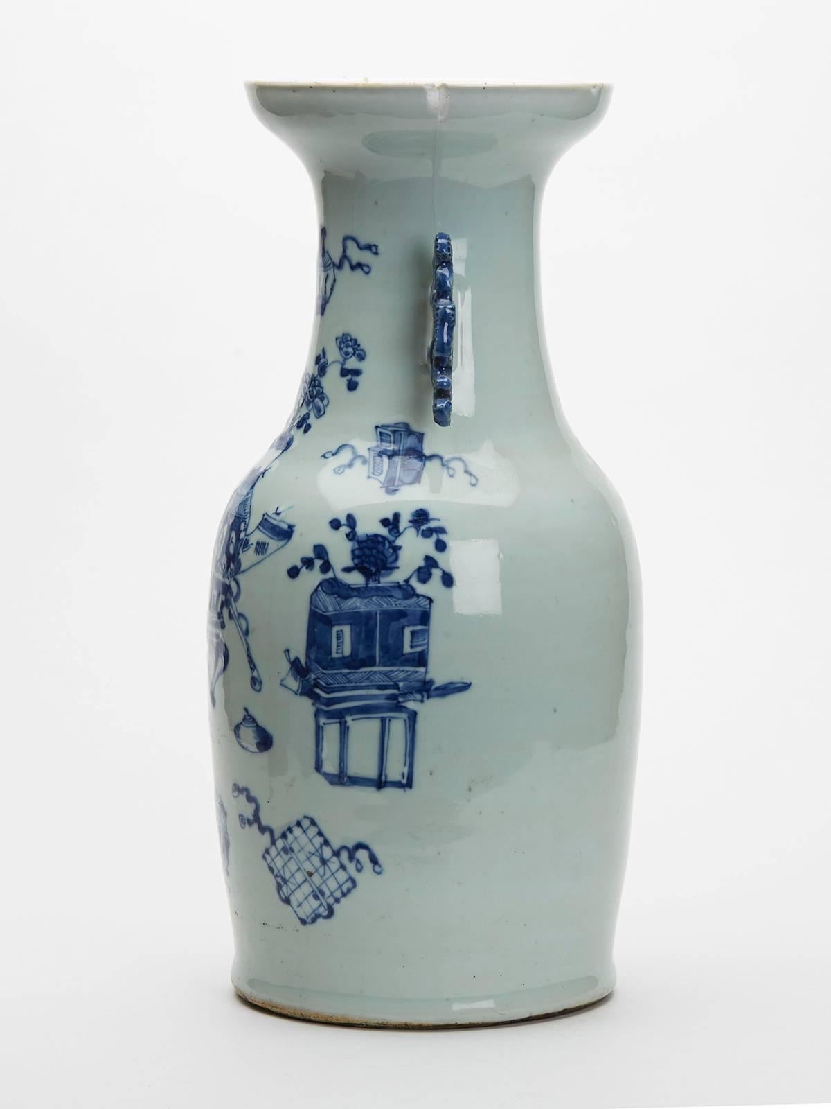 A fine antique Chinese porcelain large baluster vase decorated with various scholars objects in low relief and decorated in underglaze blue within a celadon glazed ground. The vase has moulded stylized handles to either side of wide funnel neck with