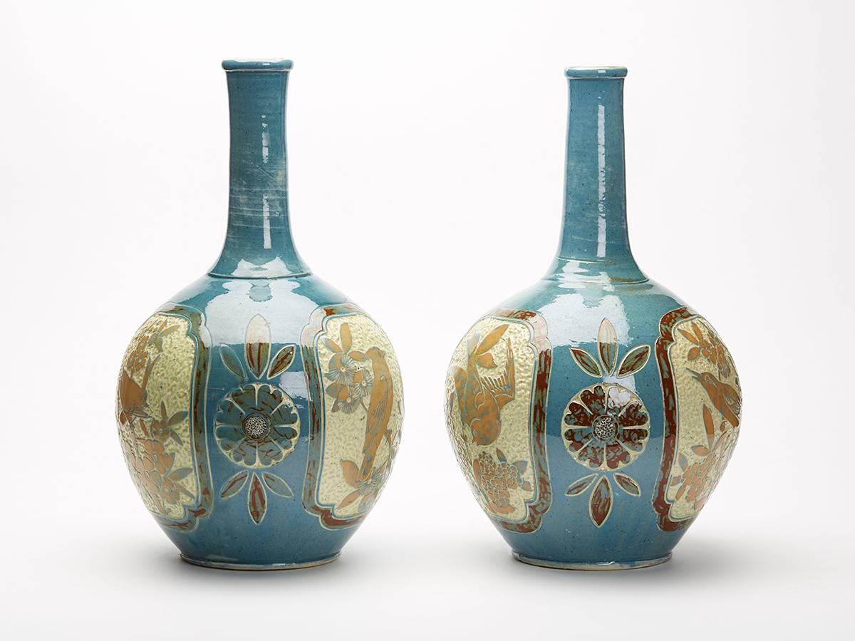 A substantial pair art pottery Sgraffito design vases by James Dewdney for Charles Brannam decorated with panels with birds the panels set between stylized floral designs. This large pair of earthenware vases are of bottle with a large rounded body