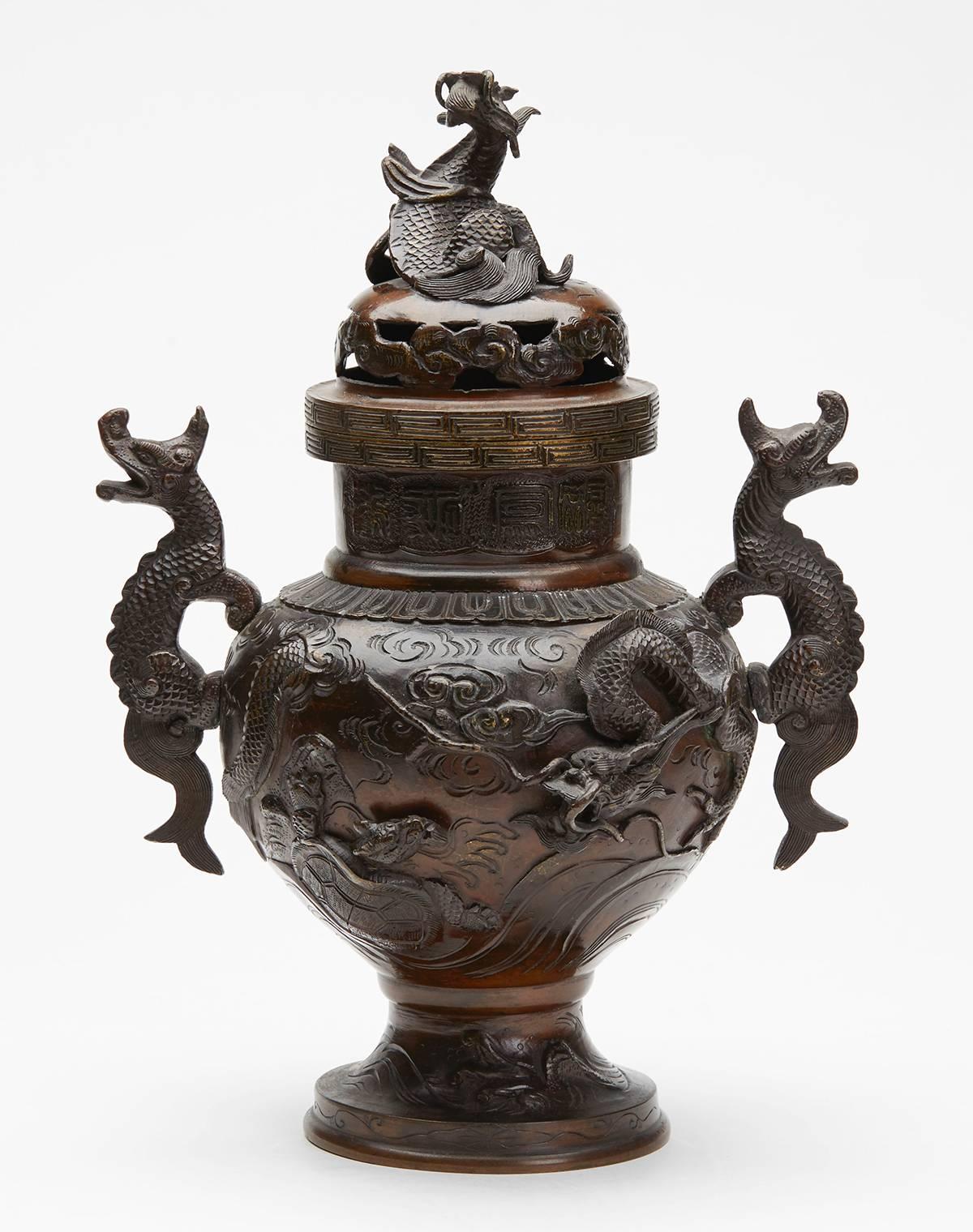 A stunning garniture three antique Japanese bronze vases, one lidded, with dragon handles, moulded in relief with dragons, phoenix birds and minogame (mythical turtles) set within moulded and scroll designs with moulded script around the neck. The