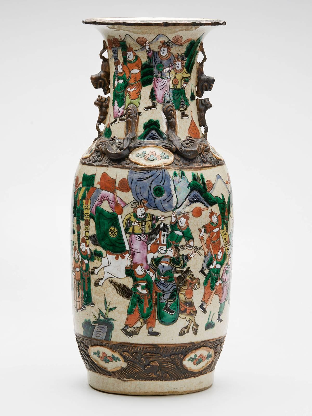A stunning and large antique Chinese craquel glaze baluster vase painted with warriors, some on foot and others on horseback within a continuous landscape above a moulded brown stained border with small oval shaped floral painted cartouches. A
