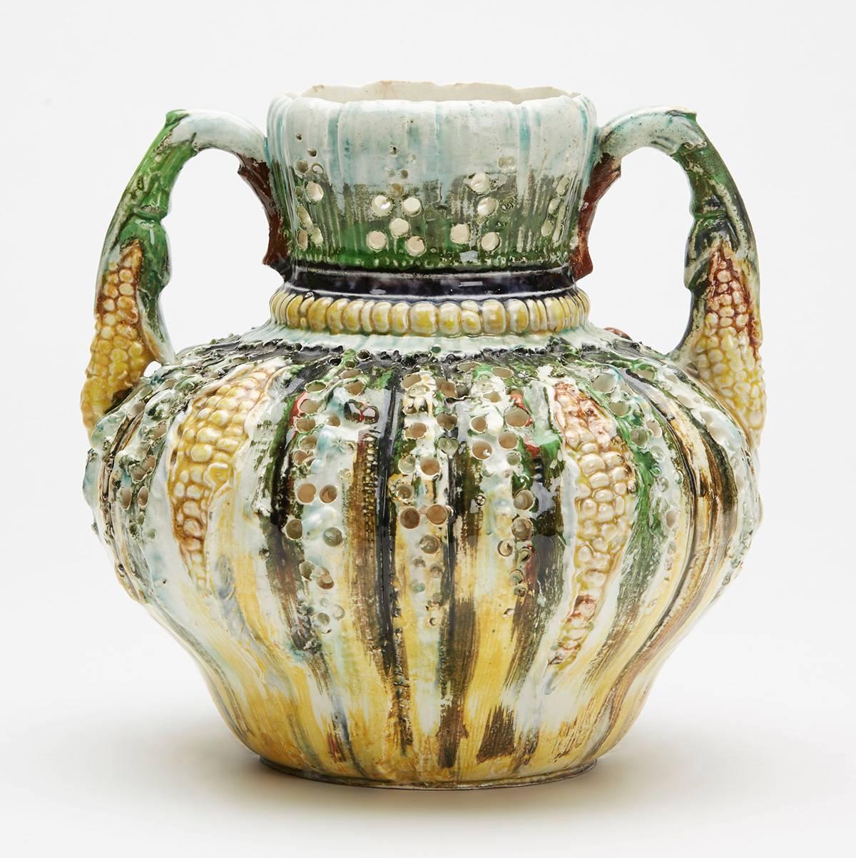 An unusual antique majolica glazed twin handled vase moulded with corn designs within a rough cast and pierced body. The lightly potted vase is of squat rounded shape with a rounded shaped neck corn and stem handles. The vase is painted in brightly