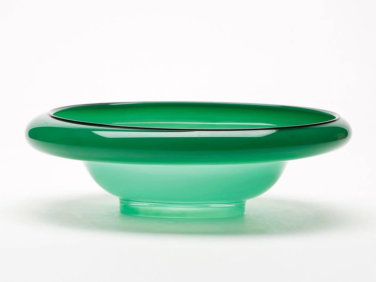 A stunning Bohemian green opaline art glass bowl of oval shape with a raised folded in rim with black glass piping around the edge designed by Michael Powolny for Loetz. This unusual bowl has some slight iridescent oil spotting with a polished