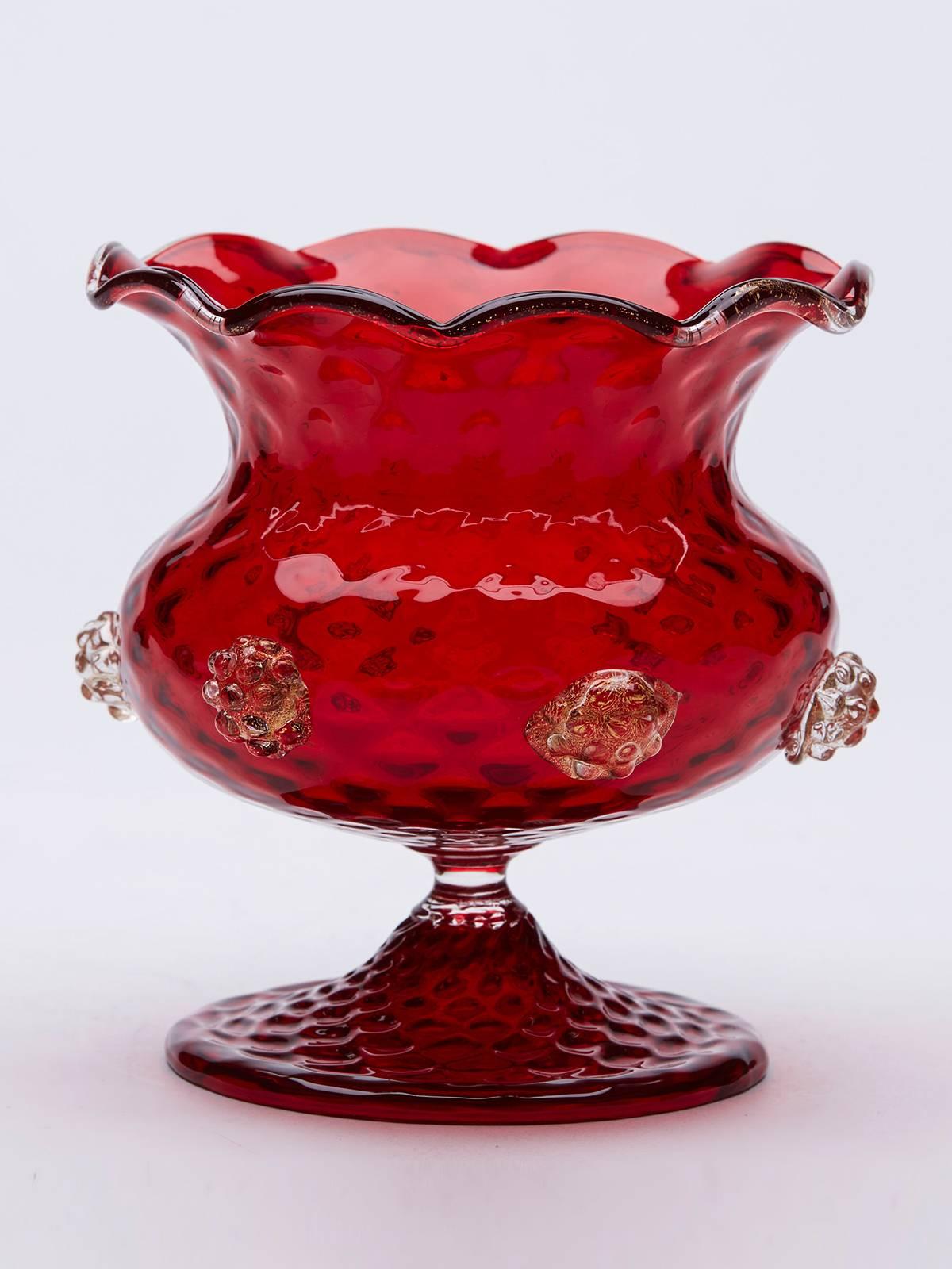A stunning Italian Mid-Century Murano red art glass pedestal bowl with clear glass and aventrine berry applications and with a piped clear glass and aventrine rim. The domed foot has a moulded textured finish with a similar pattern to the body of