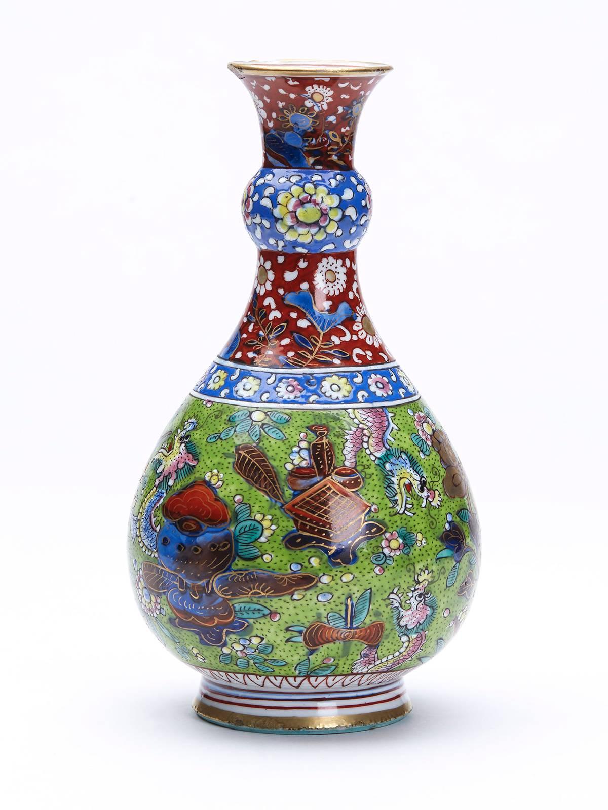 An exceptionally finely painted antique Chinese Kangxi (1662-1722) overpainted (clobbered) porcelain bottle shaped vase with garlic neck painted with dragons and a wading bird in a pond set amidst flowers with auspicious objects on a green ground