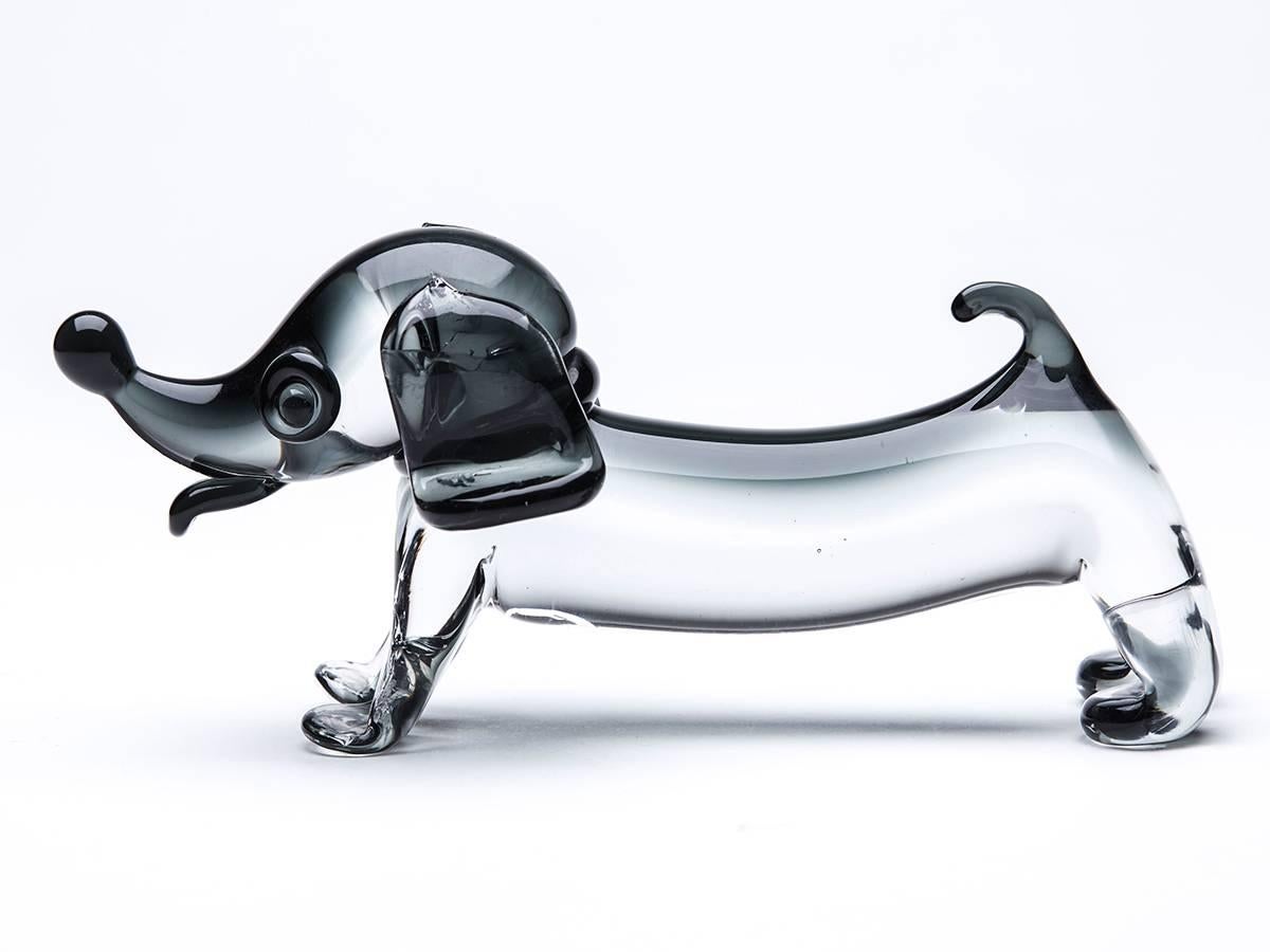 A delightful vintage Italian Murano glass figure of a dachshund dog in grey tinted glass. This novelty figure stands on all fours with a small raised tail and large head with pronounced glass moulded features. The figure is not marked but attributed
