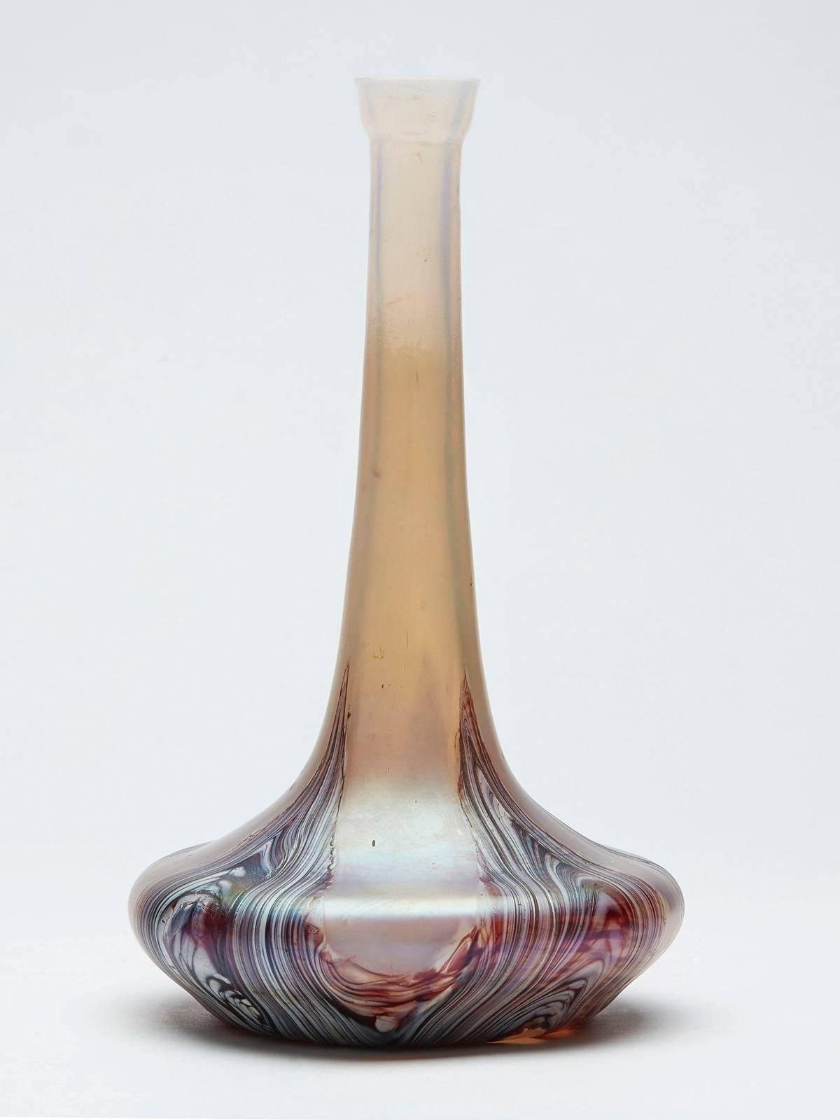 A Kralik art glass vase of bottle shape with marbled designs within an opalescent glass body with a squat wide rounded base and tall slender neck with a cup shaped top. The vase is decorated with red brown and white swirled designs gathered together