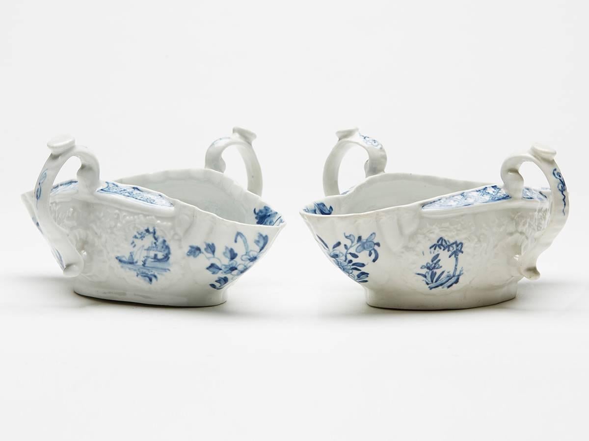 A rare pair antique Worcester blue and white double ended twin handled sauce boats each decorated with floral mouldings, moulded side fitted twin handles and painted to the inside base with Chinese Island scenes with smaller Chinese panels to the