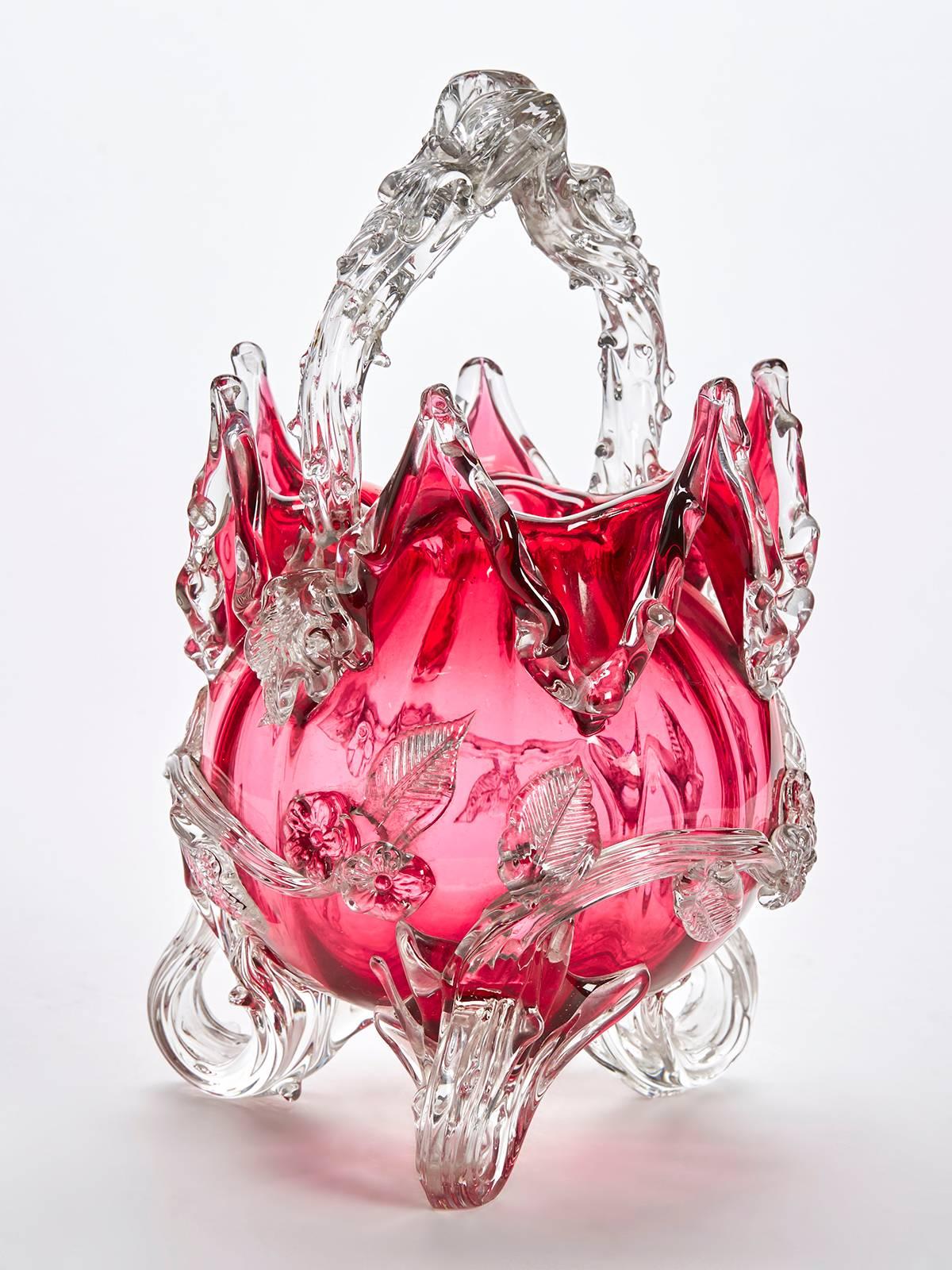 A rare and stunning large Victorian cranberry glass basket raised on three clear glass loop feet with moulded clear glass stems applied with flowers and leaves, a raised clear glass twin handle applied with thorns and with a clear glass edge to the