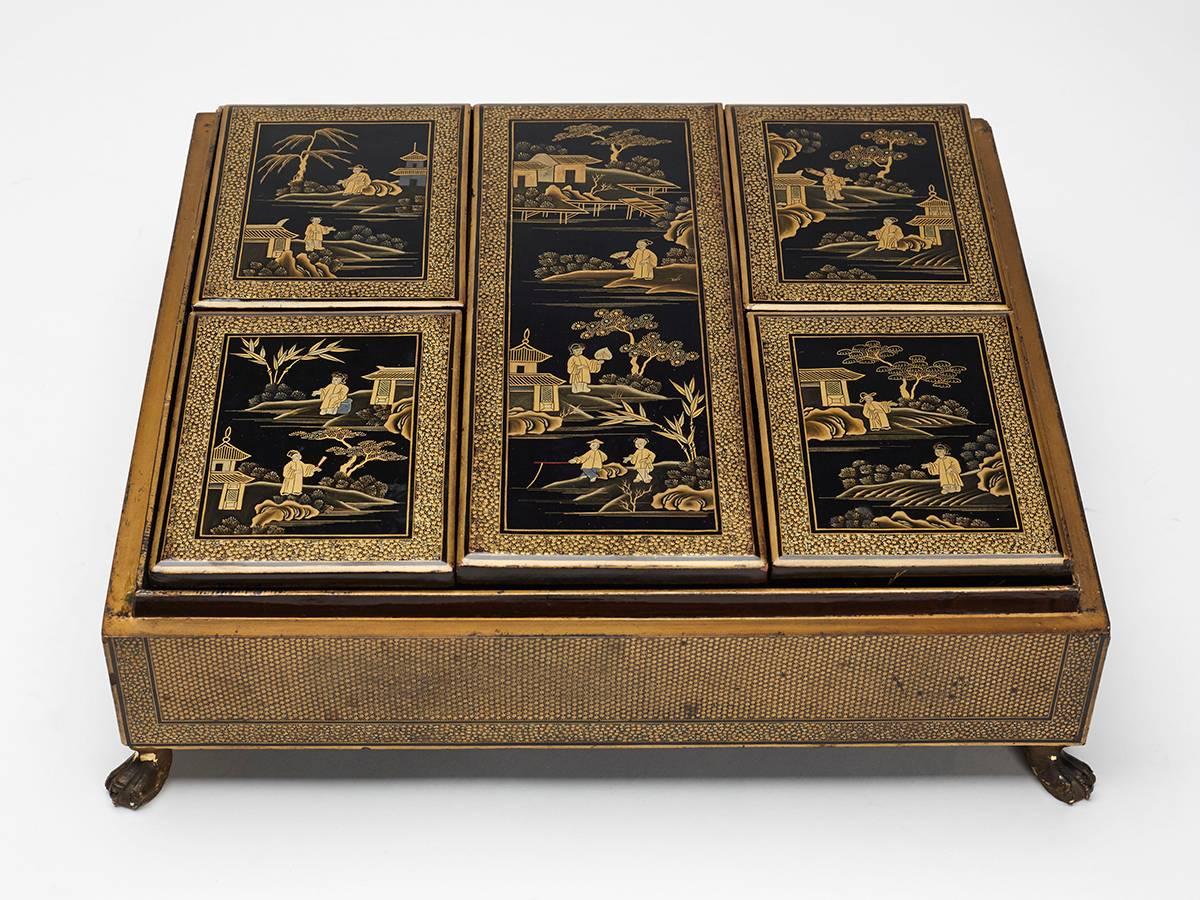 An exceptional antique Chinese gold and black lacquer games box raised on four paw feet with a domed lift off cover decorated with figural landscape panels in gilded lacquer colours on a black ground. The cover lifts off to reveal five lidded