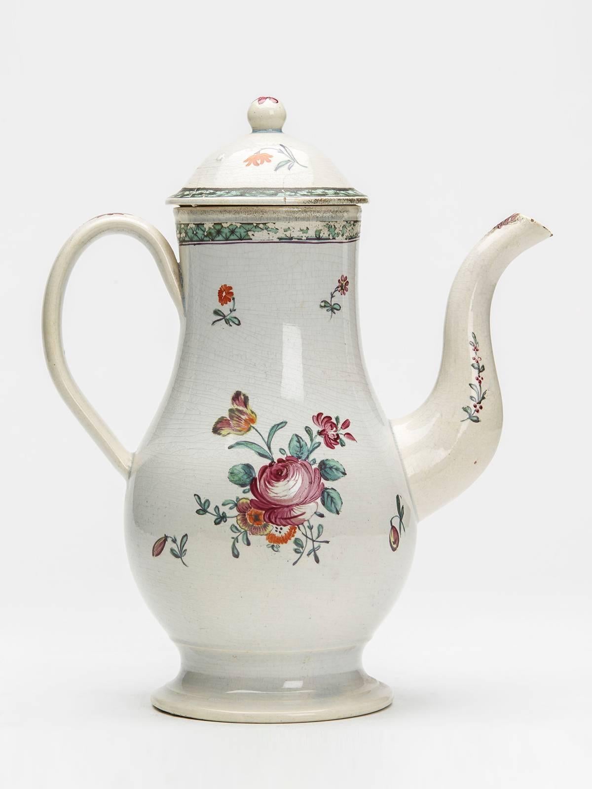 An antique Staffordshire pearlware coffee pot and cover hand-painted in coloured enamels with floral designs. This elegant and lightly potted coffee pot stands on a rounded pedestal foot with a simple loop handle, raised pouring spout and domed