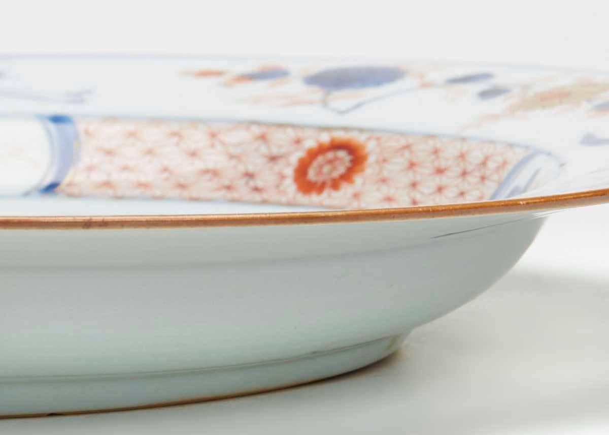 An antique Chinese dish or large plate decorated in the Imari pattern with birds in a landscape set within a decorative border and with birds and floral designs around the rim. This finely made porcelain dish is of rounded form with a slightly