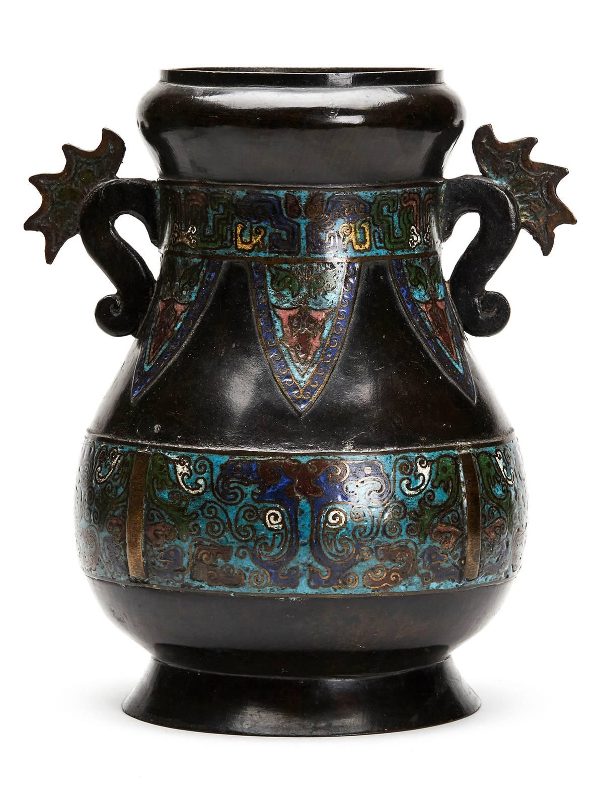 A large and impressive antique Chinese archaic form twin handled bronze vase with cloisonne enamel designs in Champleve style. The rounded bulbous vase has a wonderful dark patina with flat snake like handles and set with bands of inlaid colored