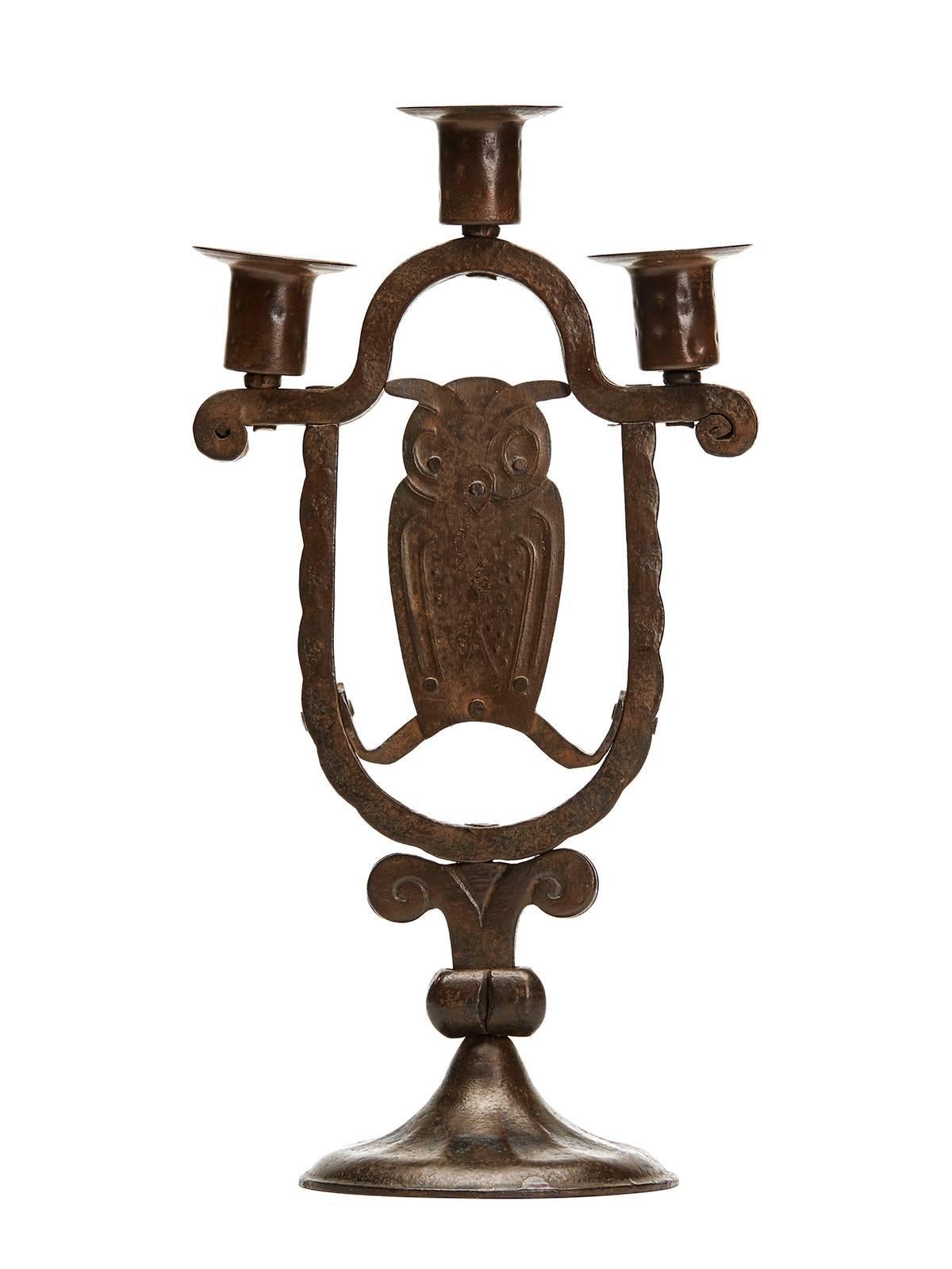 A stylish Austrian Secessionist Industrial art patinated iron triple owl candlestick by Hugo bergere. The candlestick stands on a wide rounded domed foot with box iron arms with a central raised candle holder and two lower mounted holders to either