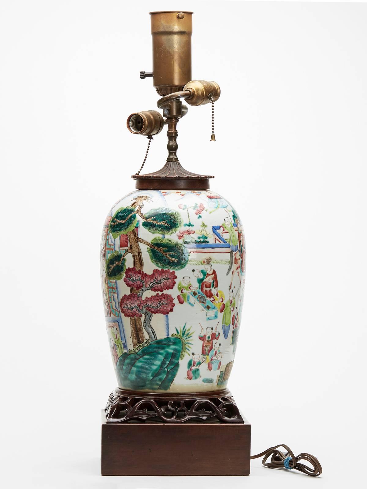 An exceptional and rare antique Chinese famille rose lamp mounted on a carved hardwood base of square form and with a petal carved hardwood top with early 20th century lamp fittings. The body of the lamp is extremely well decorated with the emperor
