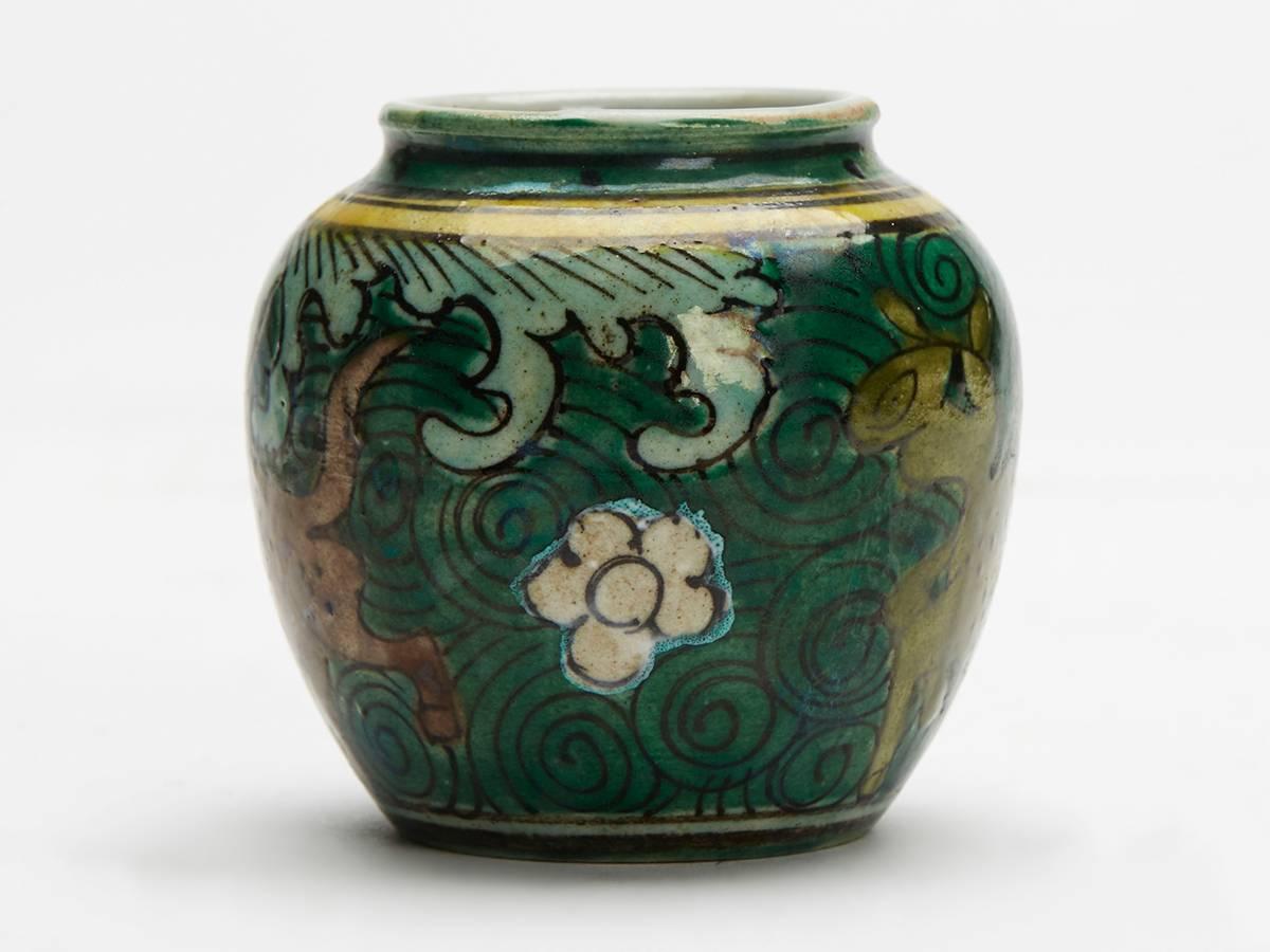 An unusual antique Chinese famille verte Kangxi style porcelain vase of rounded baluster shape painted with stylized grotesque animals set against a swirl patterned ground. The small vase is decorated in shades of green, yellow, brown and white with