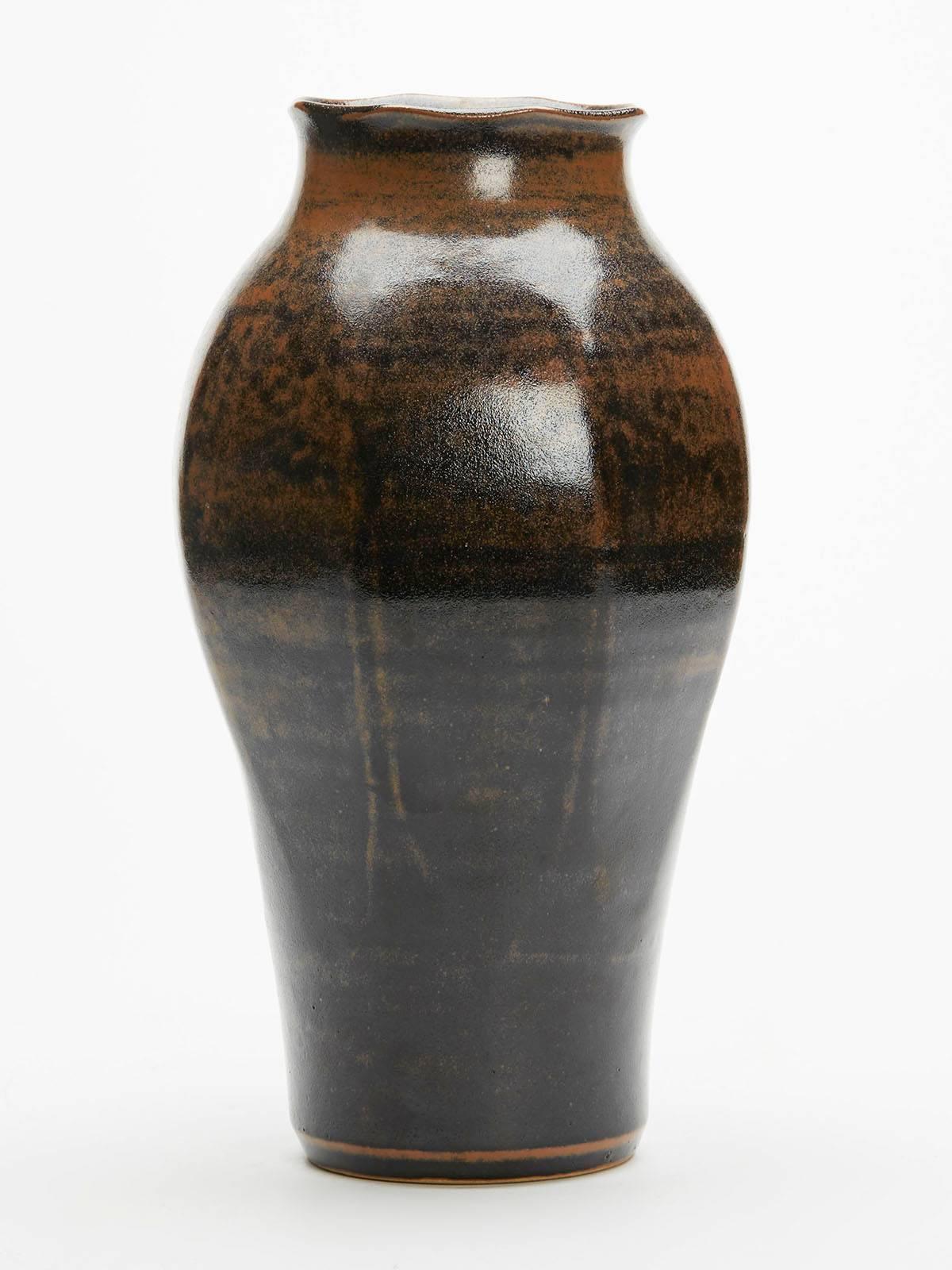 A vintage Ken Halsall Studio Pottery tenmoku glazed octagonal panelled vase. The stoneware vase stands on a narrow rounded foot the body graduating into octagonal shape with a shaped rounded top. Decorated in black on brown tenmoku glazes the vase