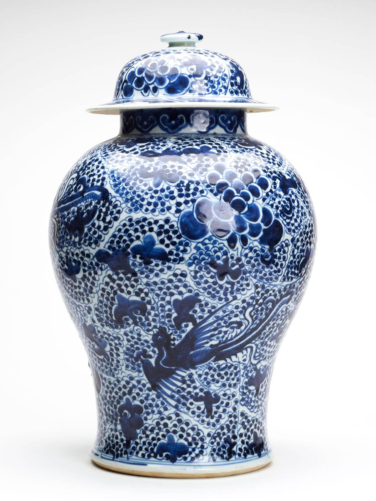 We offer this stunning and large antique Chinese Kangxi lidded jar or vase decorated with phoenix birds amidst flowering peony and dating between 1662 and 1722. This large baluster shaped porcelain jar stands on a wide rounded unglazed foot rim with