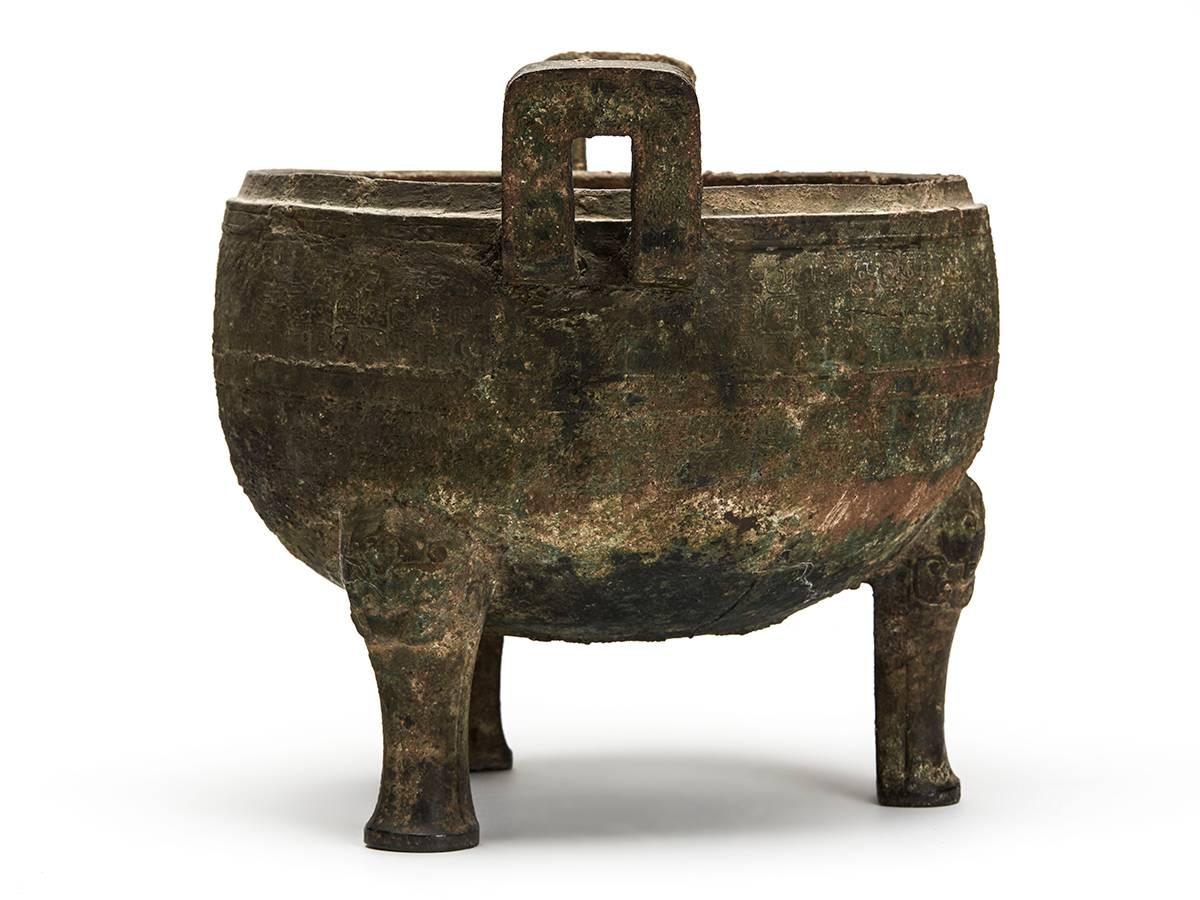 An ancient Chinese bronze ceremonial ding, believed to date from the mid-late Shang dynasty. The ding is of the typical shape of the Shang period with tripod feet and two facing handles. Derived from common ceramic shapes, bronzes of this type had