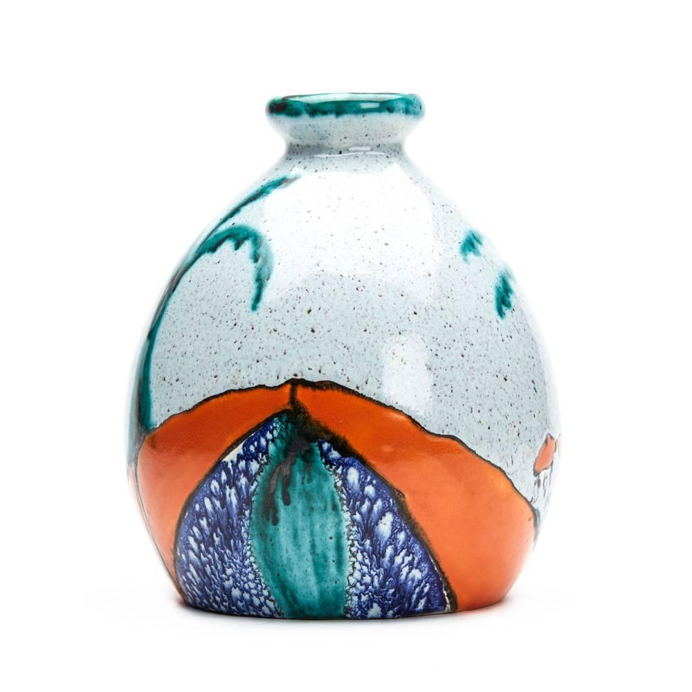 A stunning and rare vintage Art Deco Belgian art pottery vase decorated with a red roof cottage set in an undulating landscape with palm like trees. The abstract styled vase is decorated in bright orange, blue and green glazes on a mottled grey