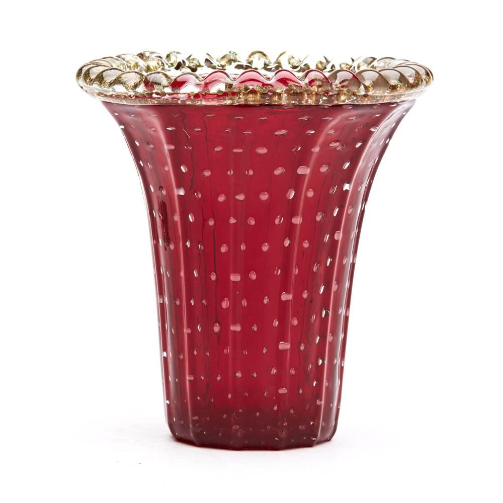 A stunning vintage Italian Murano art glass flared trumpet vase with moulded in deep red glass with ribbed body with controlled bubble inclusions with an applied decorative clear glass rim with gold aventurine inclusions. The vase has a polished
