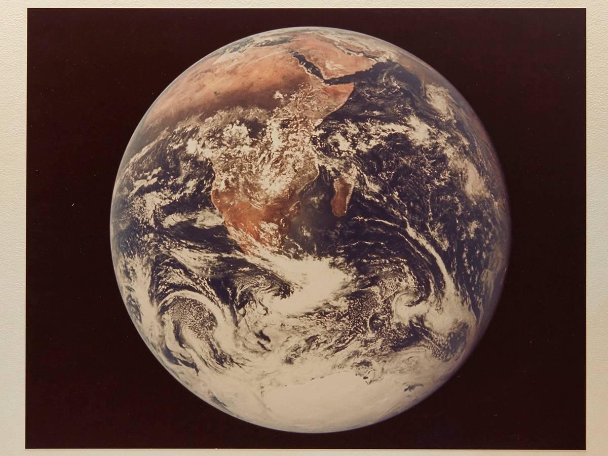 An original and rare mounted color photograph showing the earth believed to be taken from the moon's surface during the final NASA Mission of the Apollo program, Apollo 17. Two of the crew, Eugene Cernan & Harrison Schmitt, spent just over three