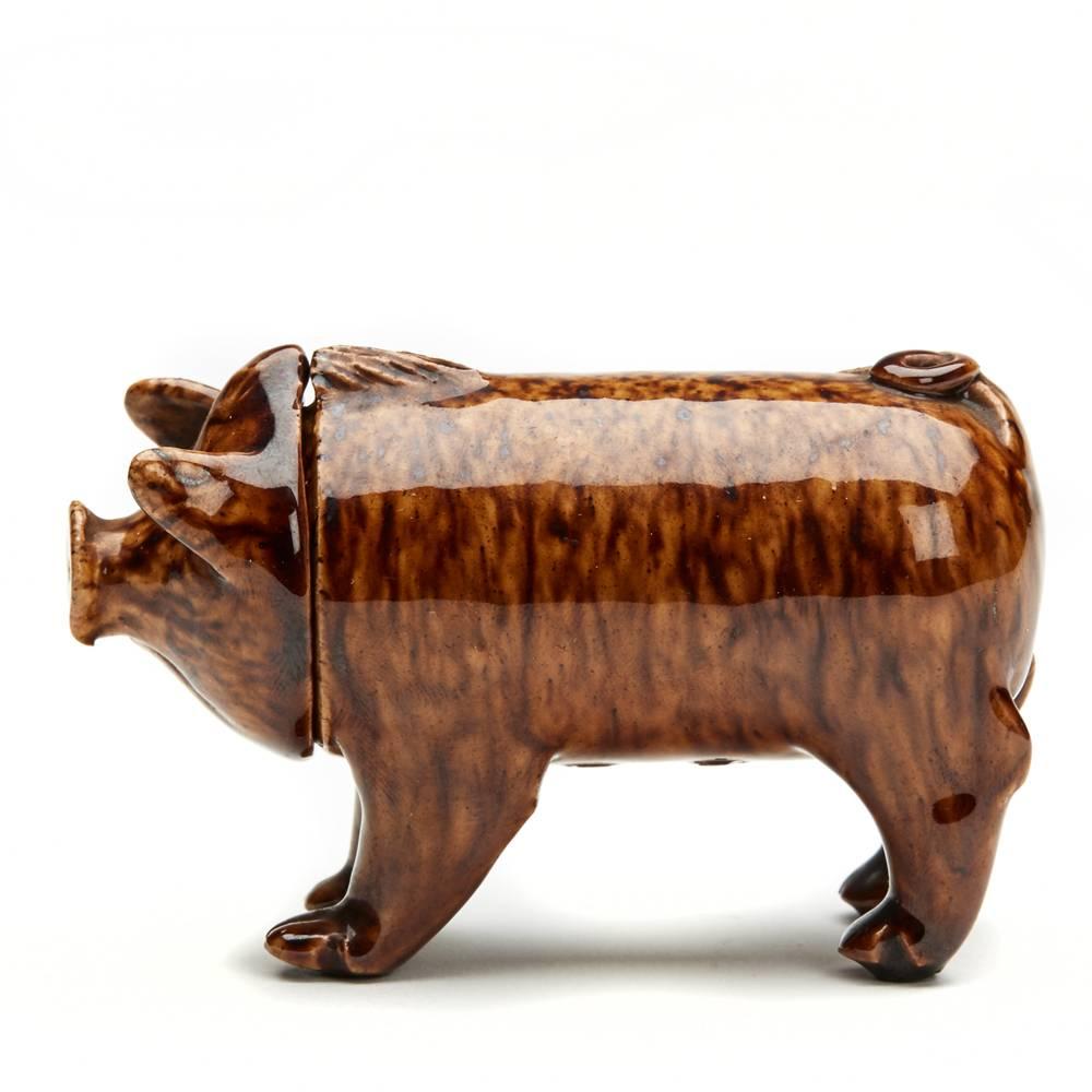 A very rare and unusual antique miniature Rye pottery figure of a Sussex Pig decorated in mottled brown glazes with a removable head. The pig is in exceptional condition the head resting on a wooden peg with shaped haunches which allow the vessel to