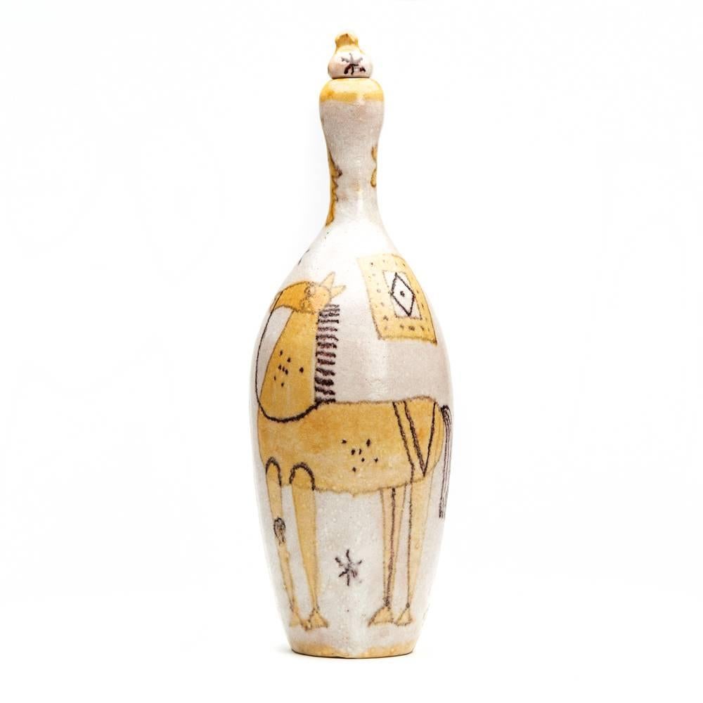 A stylish vintage Italian art pottery bottle and stopper painted with horses by Guido Gambone (1909-1969). The tall stoneware bottle is decorated in a soft white slightly textured glaze with yellow and black painted designs with horses and a face at