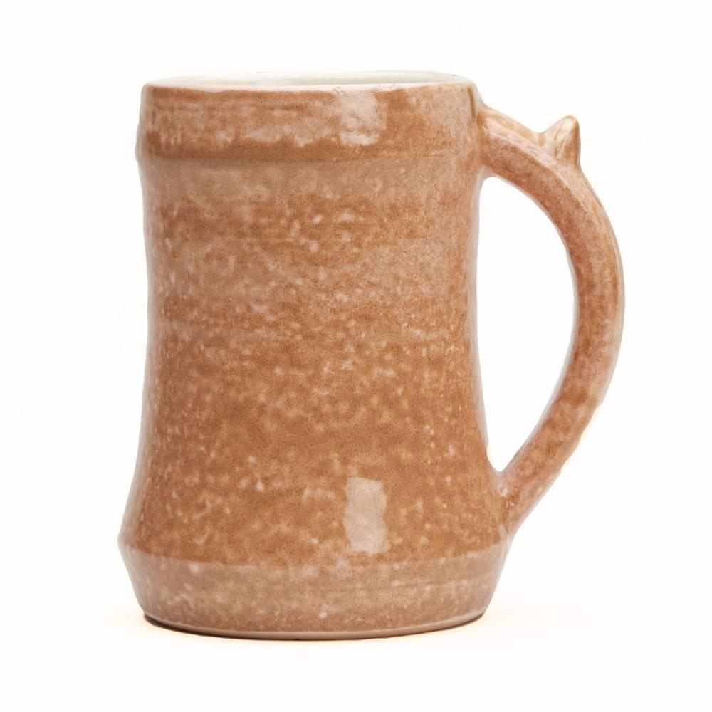 A stylish Studio Pottery mug made at Loughton Pottery by Thomas Weir Howard. The shaped stoneware mug has a loop handle with thumb rest and is decorated with mottled brown glazes over a peach coloured ground, the inner mug decorated in cream