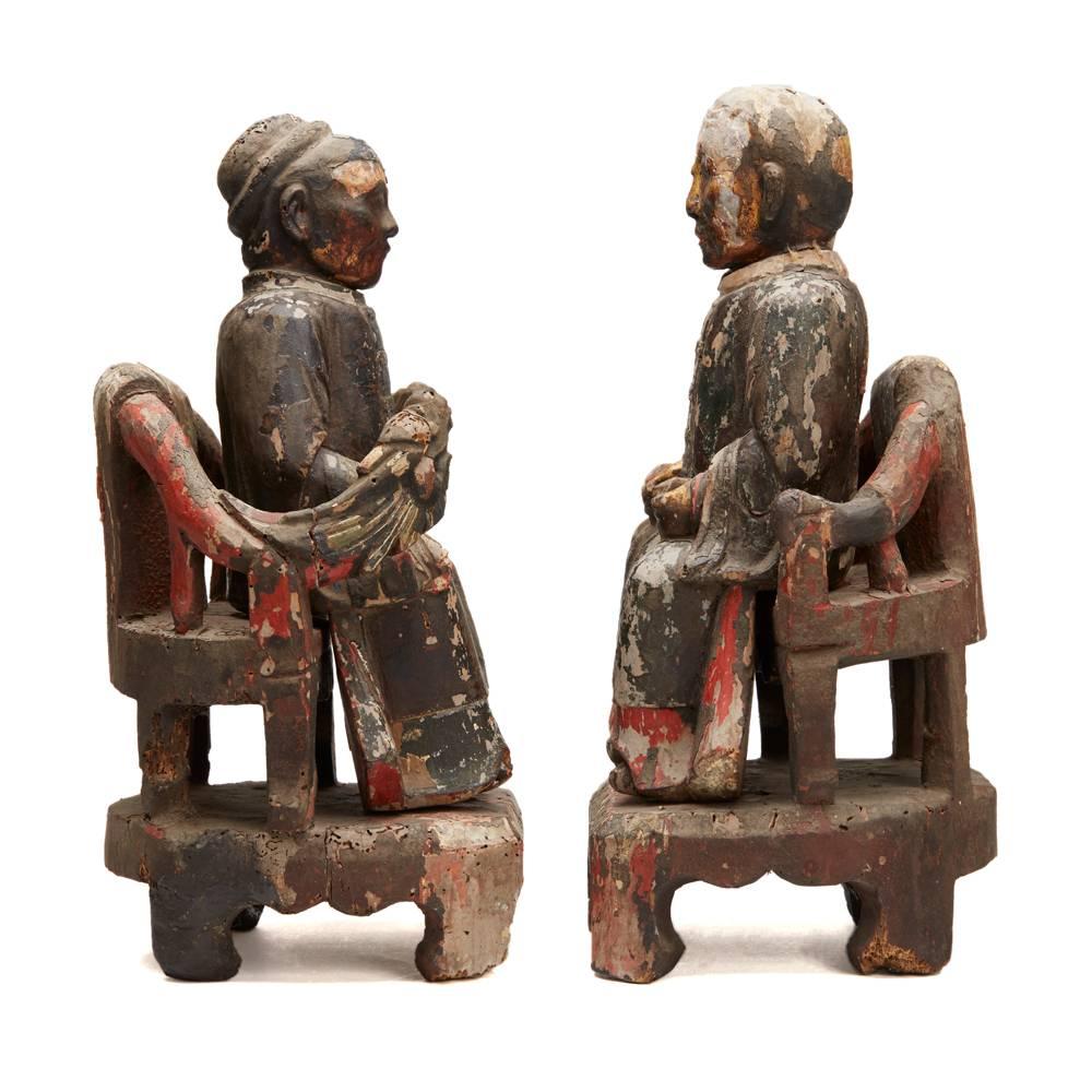 A rare pair early Chinese Qing carved wood figures comprising of an Earth God and Earth Grandma each sat on a detachable throne. The figures are lacquered in black and red with gilding with painted detail and patterns visible within the residue on