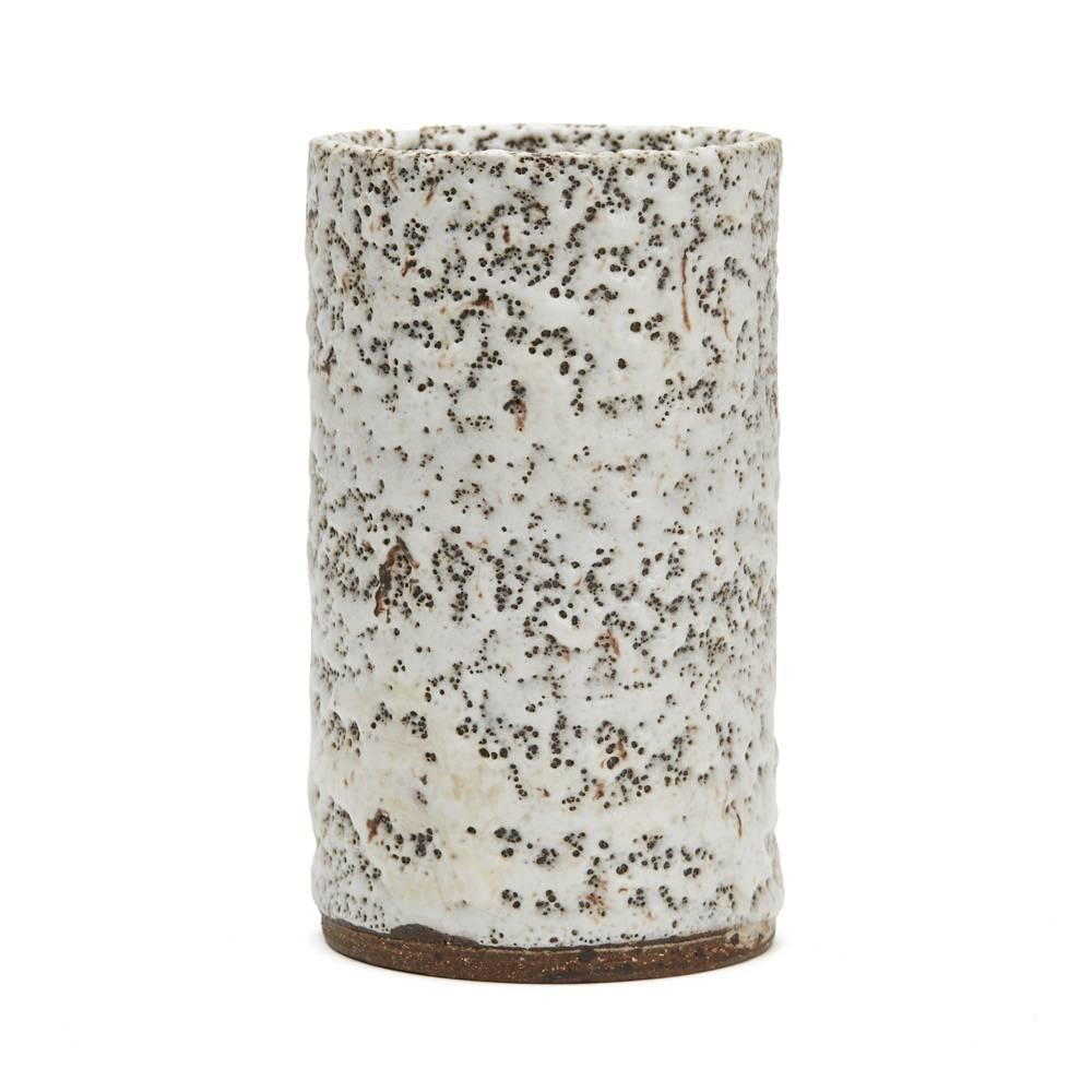 A stunning vintage British Studio Pottery stoneware vase by Lucie Rie, of cylindrical shape applied in thick white textured glazes with unevenly distributed black pitting the glazes flowed unevenly over the body of the vase both to the inside and