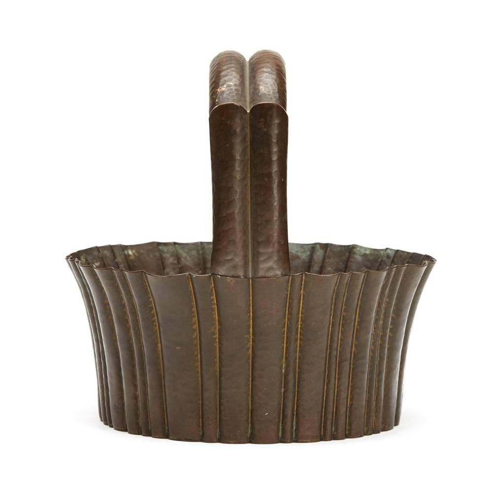 A Josef Hoffmann brass, hand-hammered handled basket, made by the Wiener Werkstatte, circa 1920. The hammered fluted basket is of rounded open shape with variously sized flutes around the rim and with a shaped fluted raised handle. Made from brass