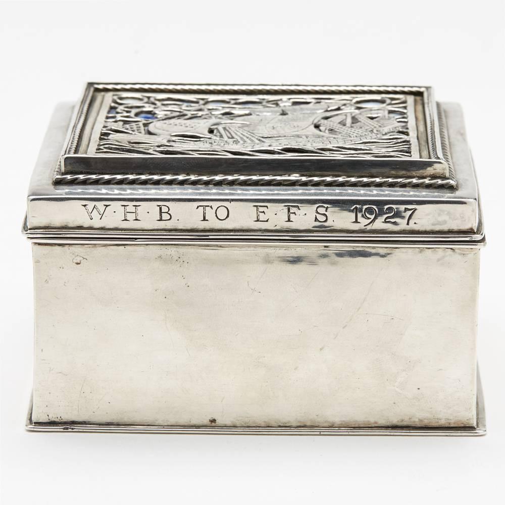 A rare and stunning Arts & Crafts Omar Ramsden silver and enamel cigarette box and cover. Rectangular in shape with a hinged cover featuring wire-work man-of-war sailing ship in rough seas design set against a blue enamel panel. The scene is set