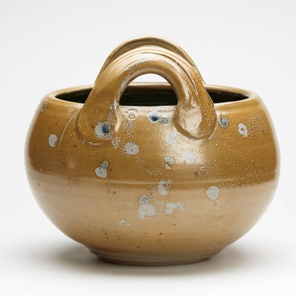 A stunning and impressive large Michael Casson (1925-2003) Studio Pottery twin handled Gozo bowl of rounded basket form with raised loop handles. The bowl is decorated in light brown glazes with spots of colour with a black glazed interior. The bowl