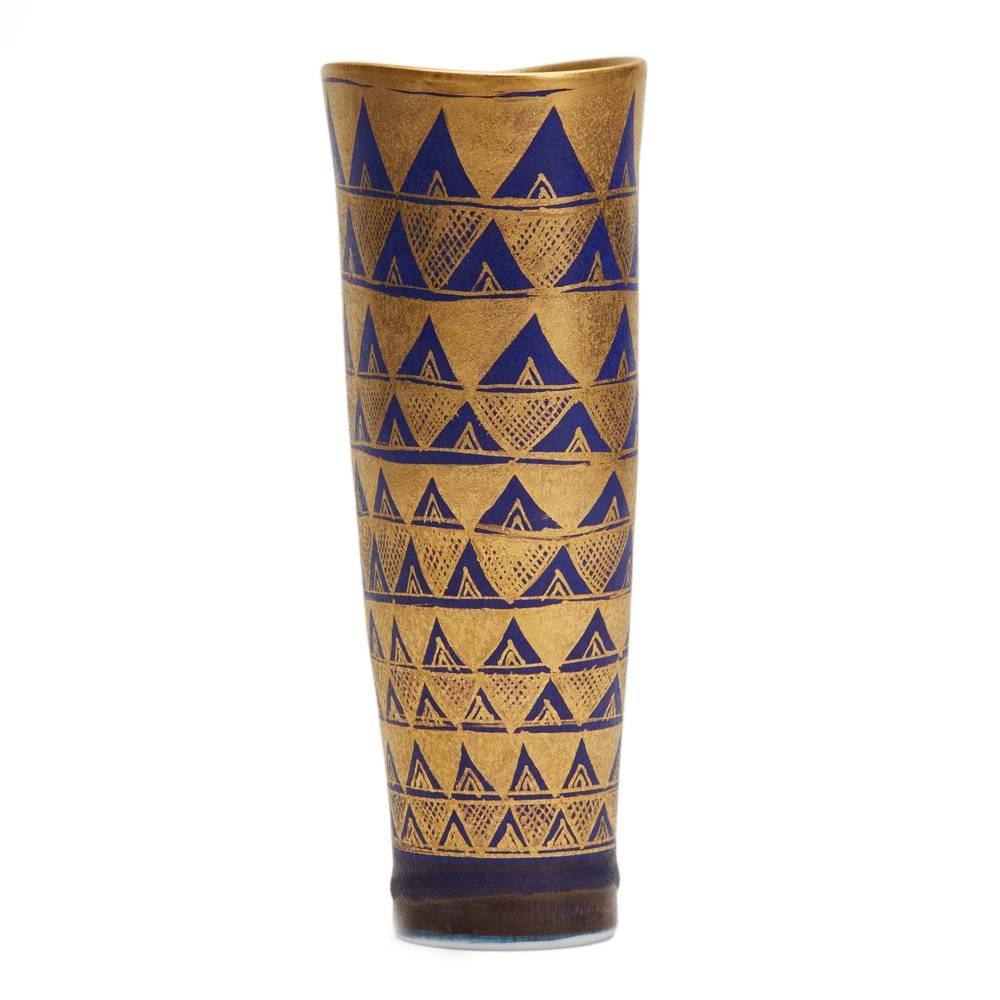 A very fine and stylish studio pottery vase of tall elegant flattened shape graduating from a narrow rounded foot and finely decorated with a richly gilded geometrical pattern on a deep blue ground. The porcelain vase has an impressed monogram to