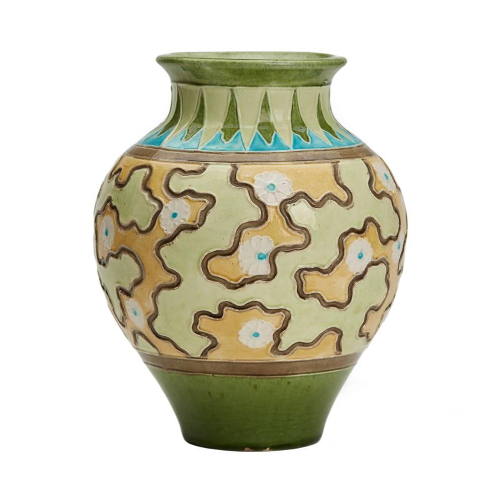 An unusual Burmantofts Faience Partie-color vase of rounded bulbous shape decorated with an incised 'jig-saw' style pattern below a patterned border. The vase is painted in tones of green, orange, brown, white and turquoise and has impressed makers