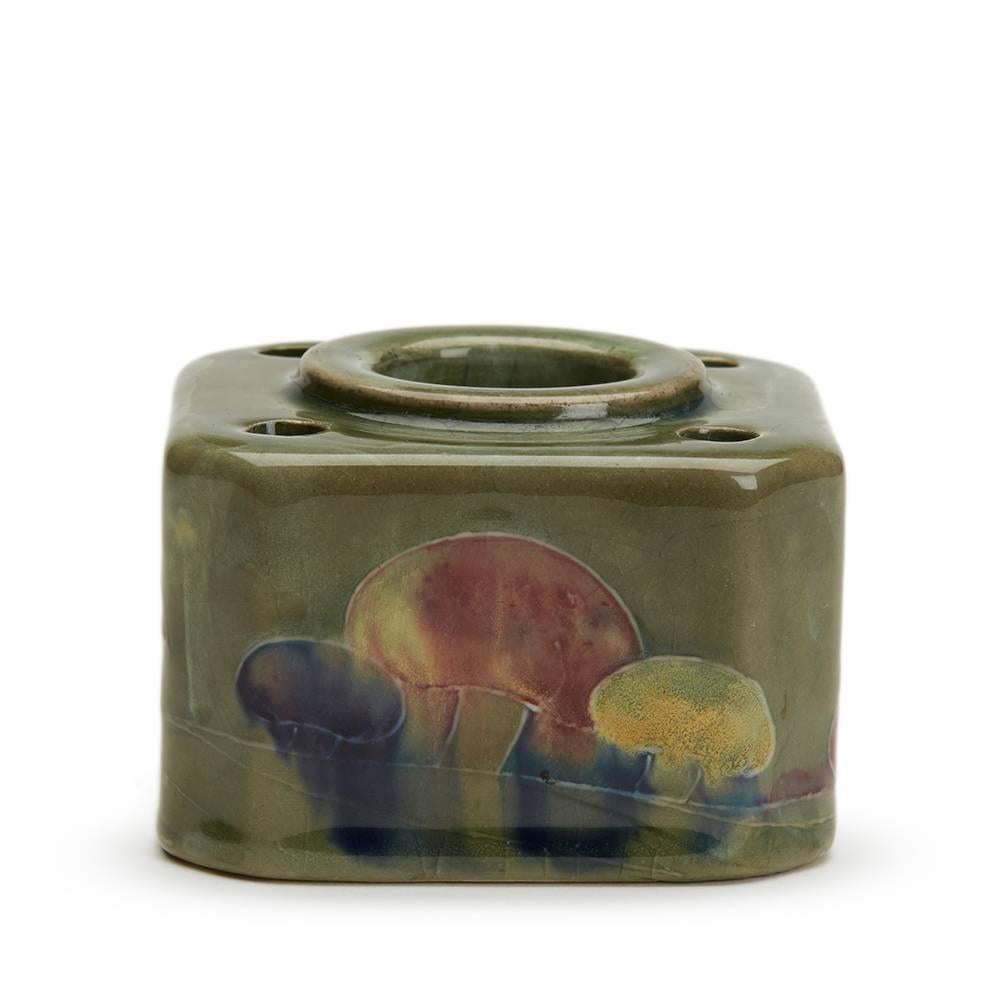 A rare William Moorcroft Claremont pattern inkwell of square shape with a central well and four pen holders. The inkwell is decorated with tubelined mushrooms in colored glazes on a mottled green ground. Probably retailed by Liberty & Co the inkwell