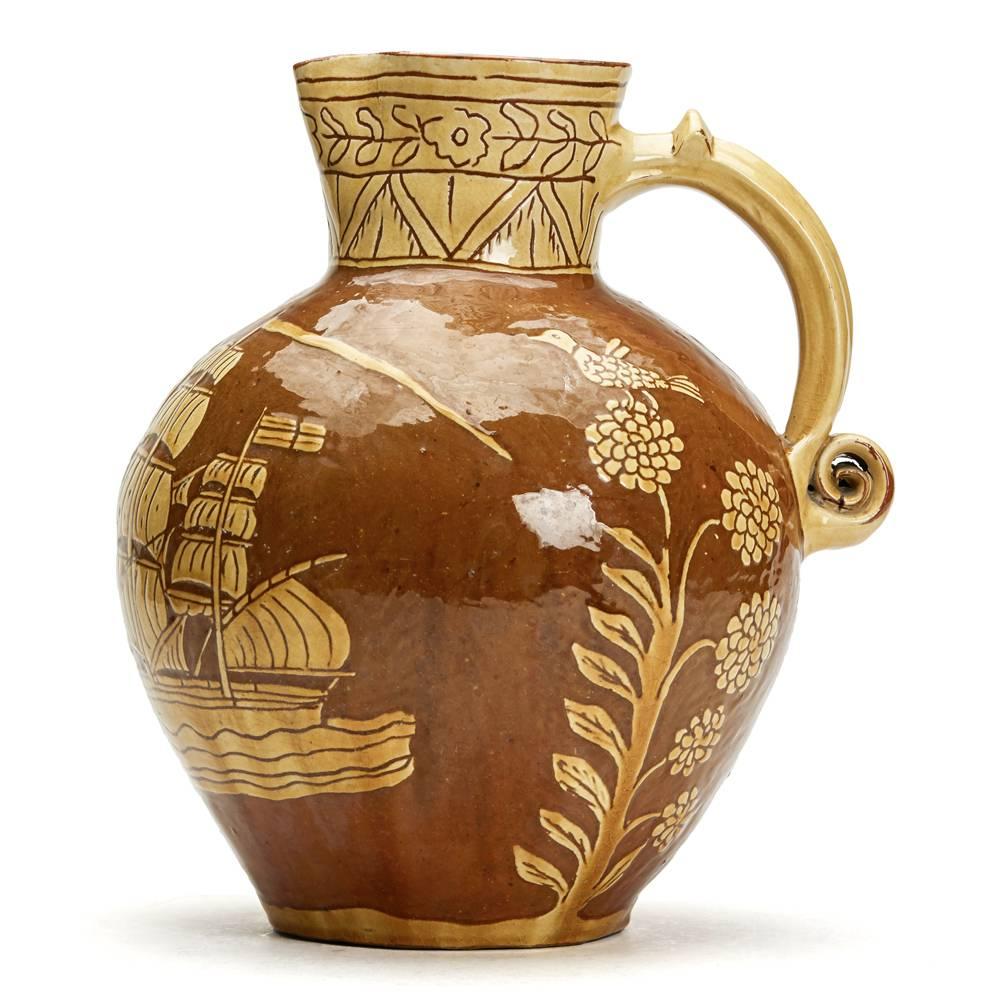 A rare Fremington pottery Nautical slipware jug of ovoid form with an applied scroll handle, incised and slip decorated in yellow with a galleon in full sail, compass, sun motif, floral designs, birds in flight and other designs on a natural glazed